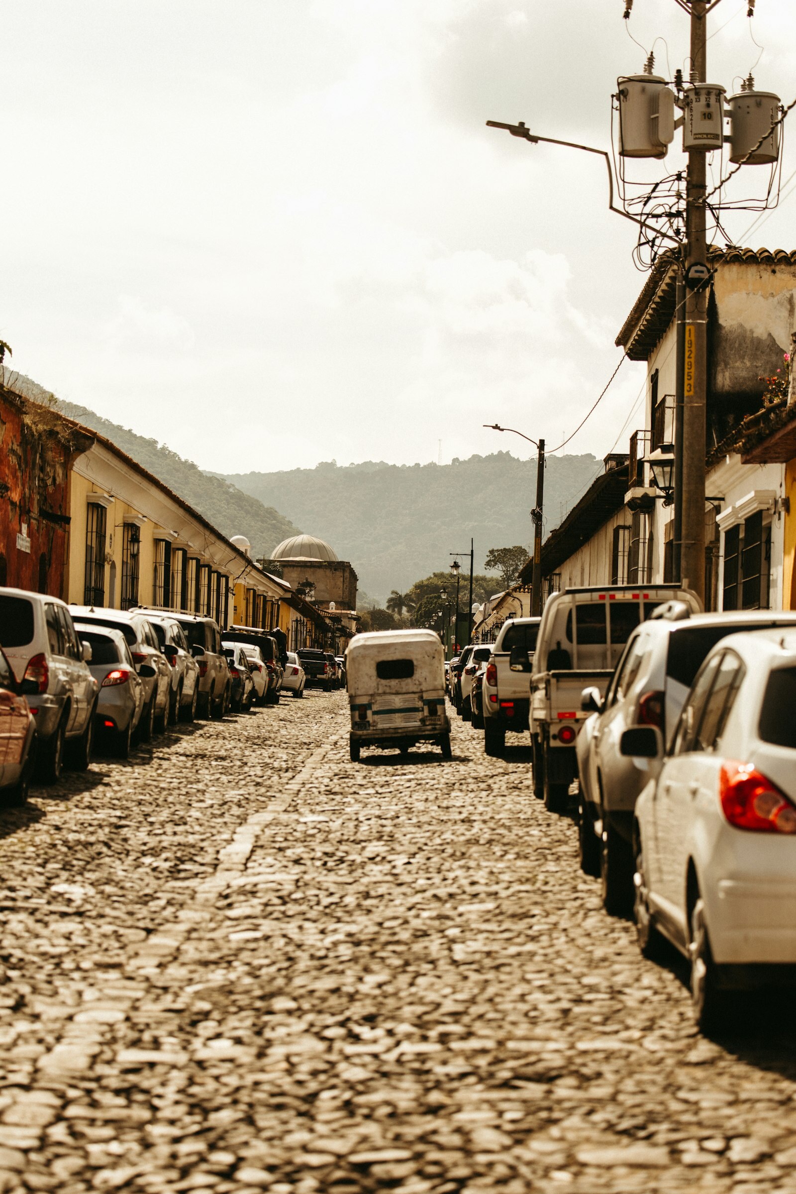 Calle empedrada en Guatemala con residentes y vehículos