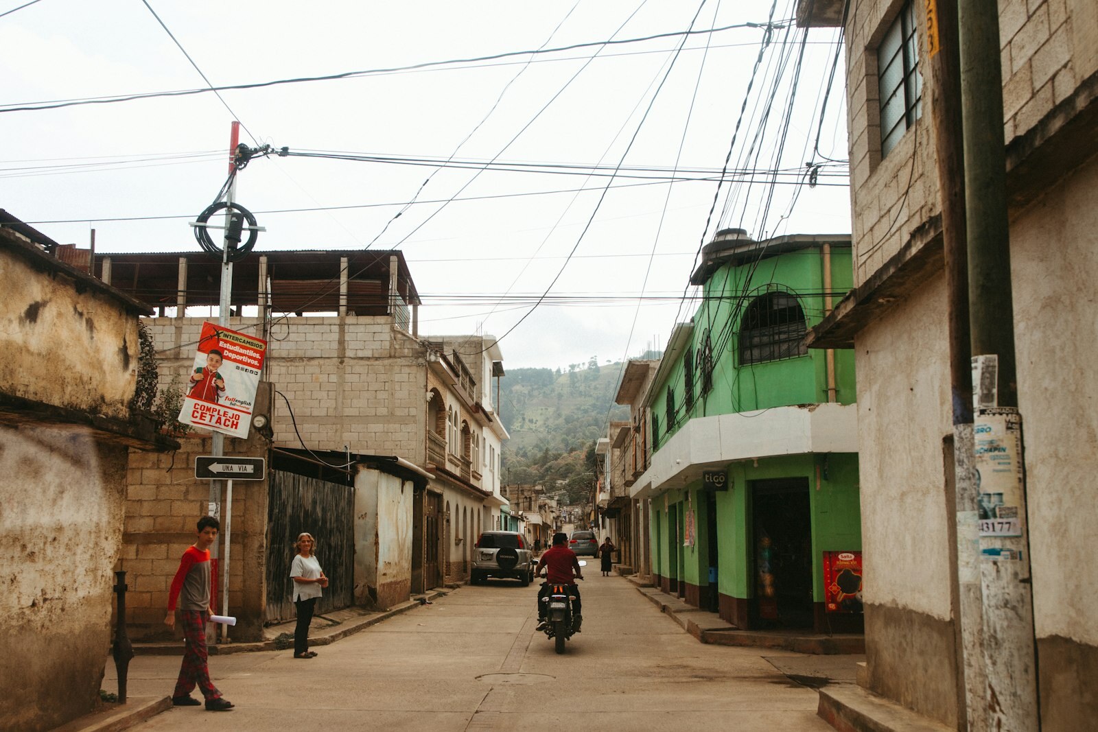 Calle guatemalteca con comercios, viviendas y transporte local