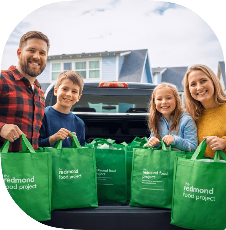 A family of four unloading their green bags from a pickup truck.