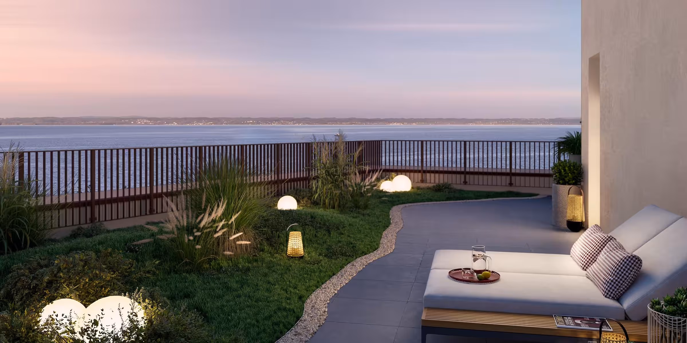 Moderne Terrasse mit Lounge-Sessel und Blick auf ruhiges Meer bei Sonnenuntergang.