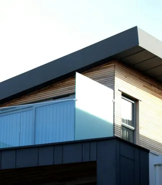 Modern building with angled roof, wood siding, and a partially open glass balcony door.