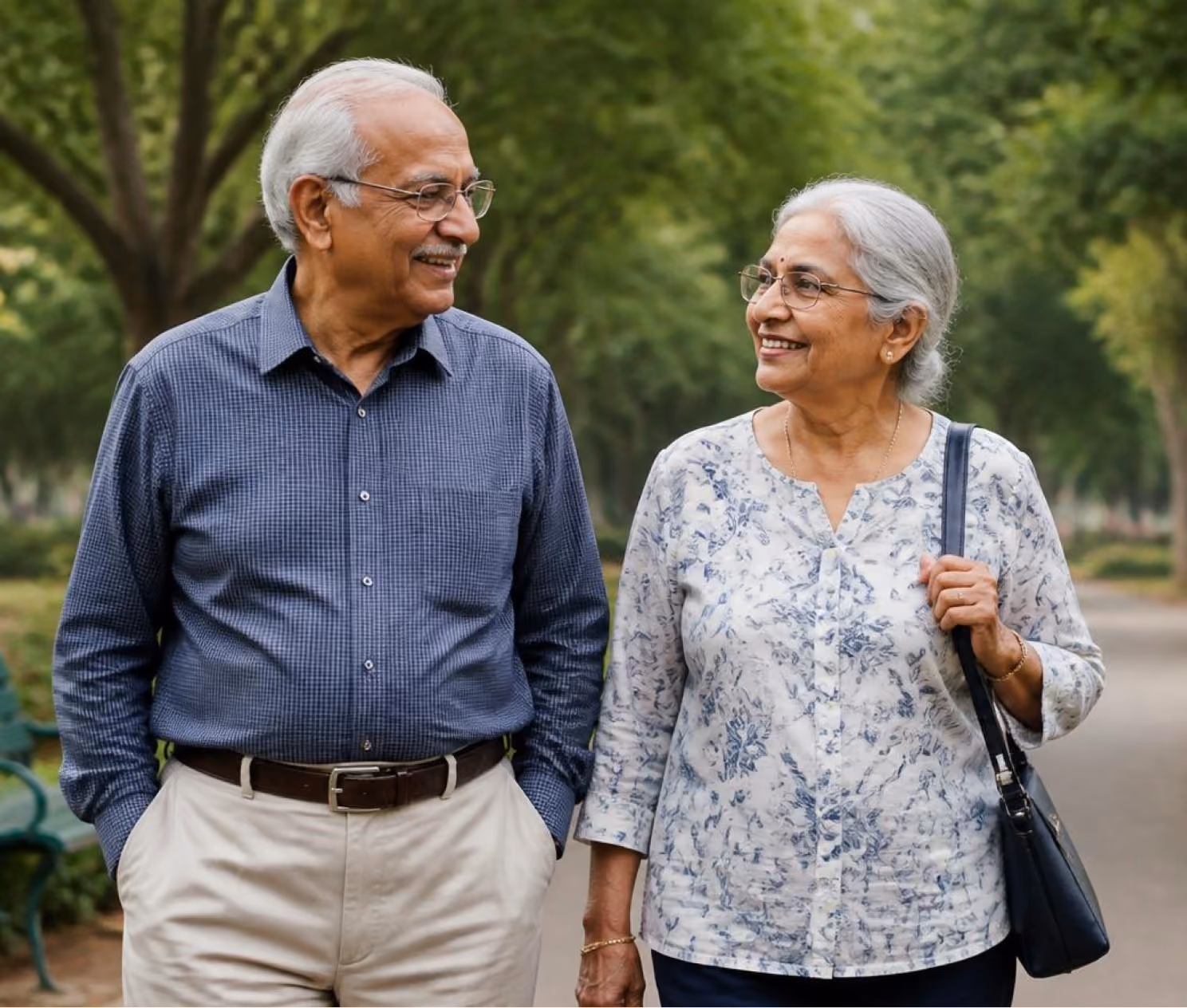 Smiling elderly man and woman walking outdoors in a tree-lined park path.