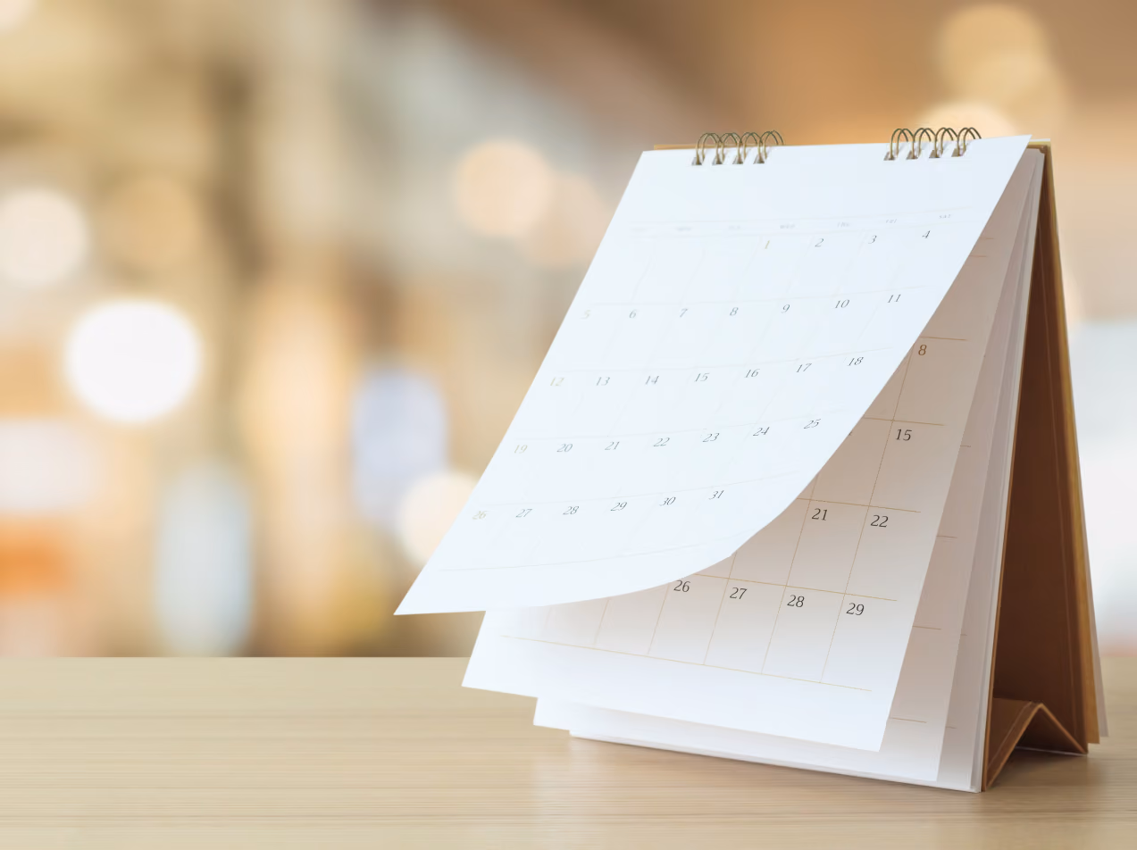 Desktop flip calendar showing blank dates with blurred warm background lighting.