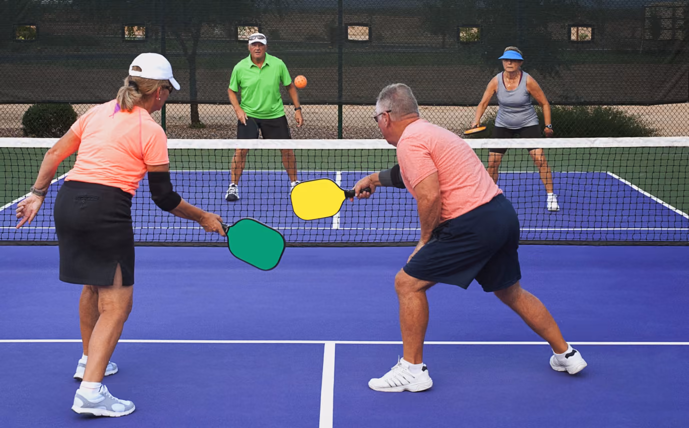 Two men and two women playing doubles pickleball on a blue court with colorful paddles.
