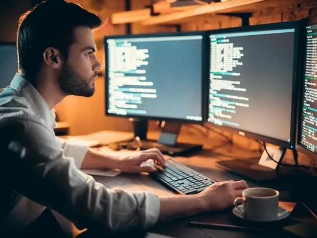Man at desk with three monitors