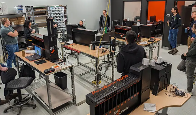 TCG Machines employees circled-up for a morning production team stand-up meeting