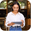 Smiling woman in a white shirt holding a tablet with a coffee cup on a saucer indoors.