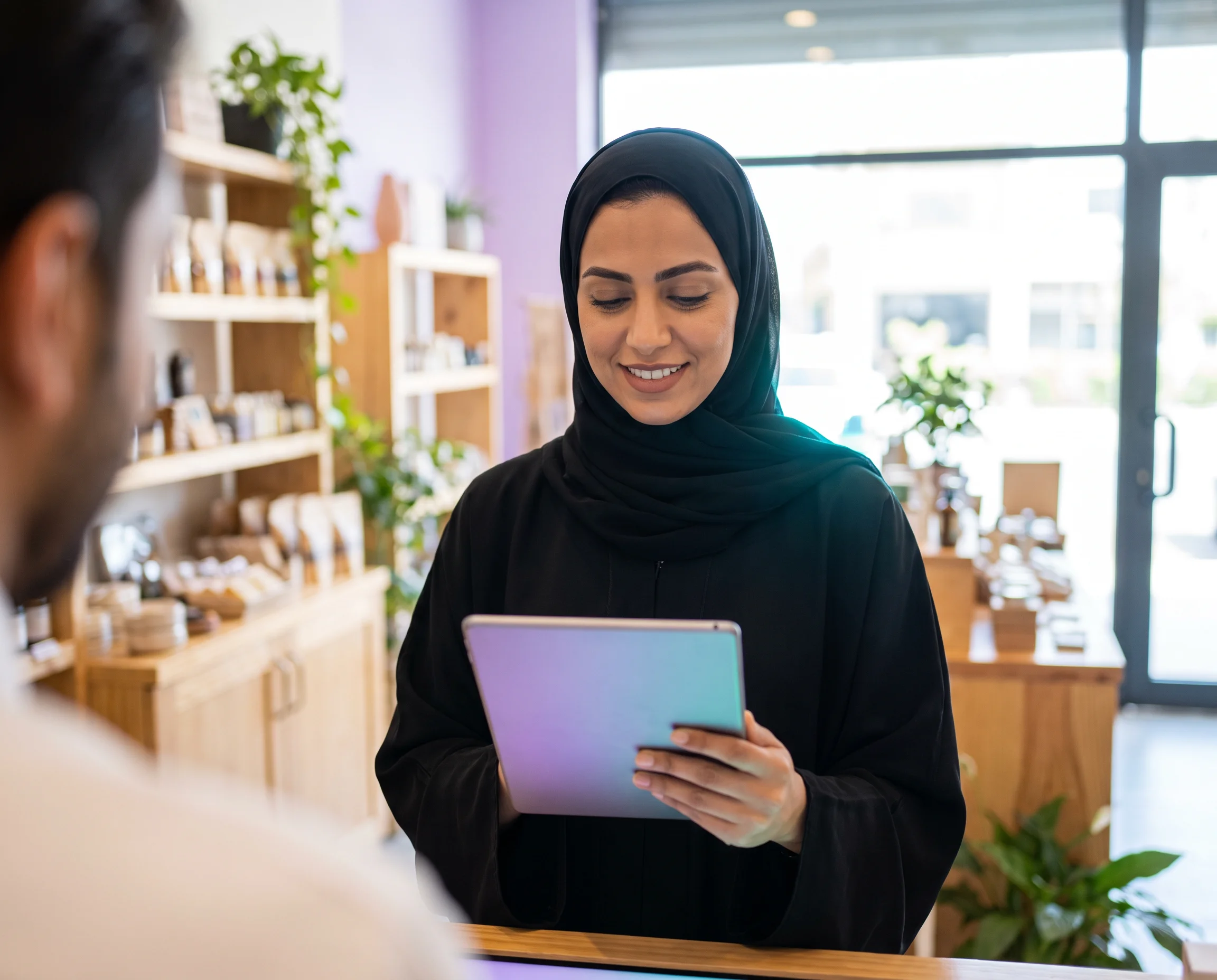 Man in traditional Middle Eastern attire working on a laptop in a modern office.