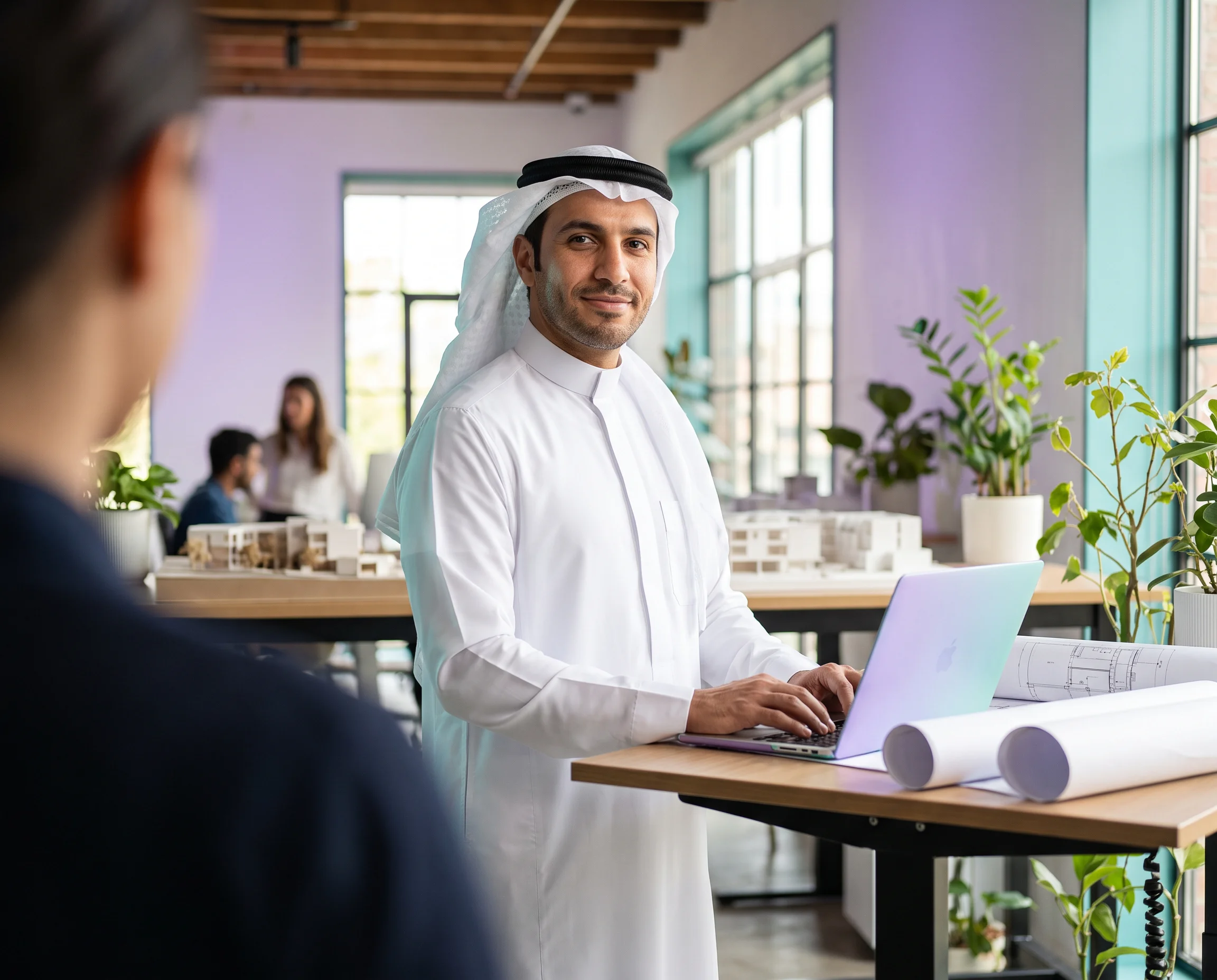 Man in traditional Middle Eastern attire working on a laptop in a modern office.