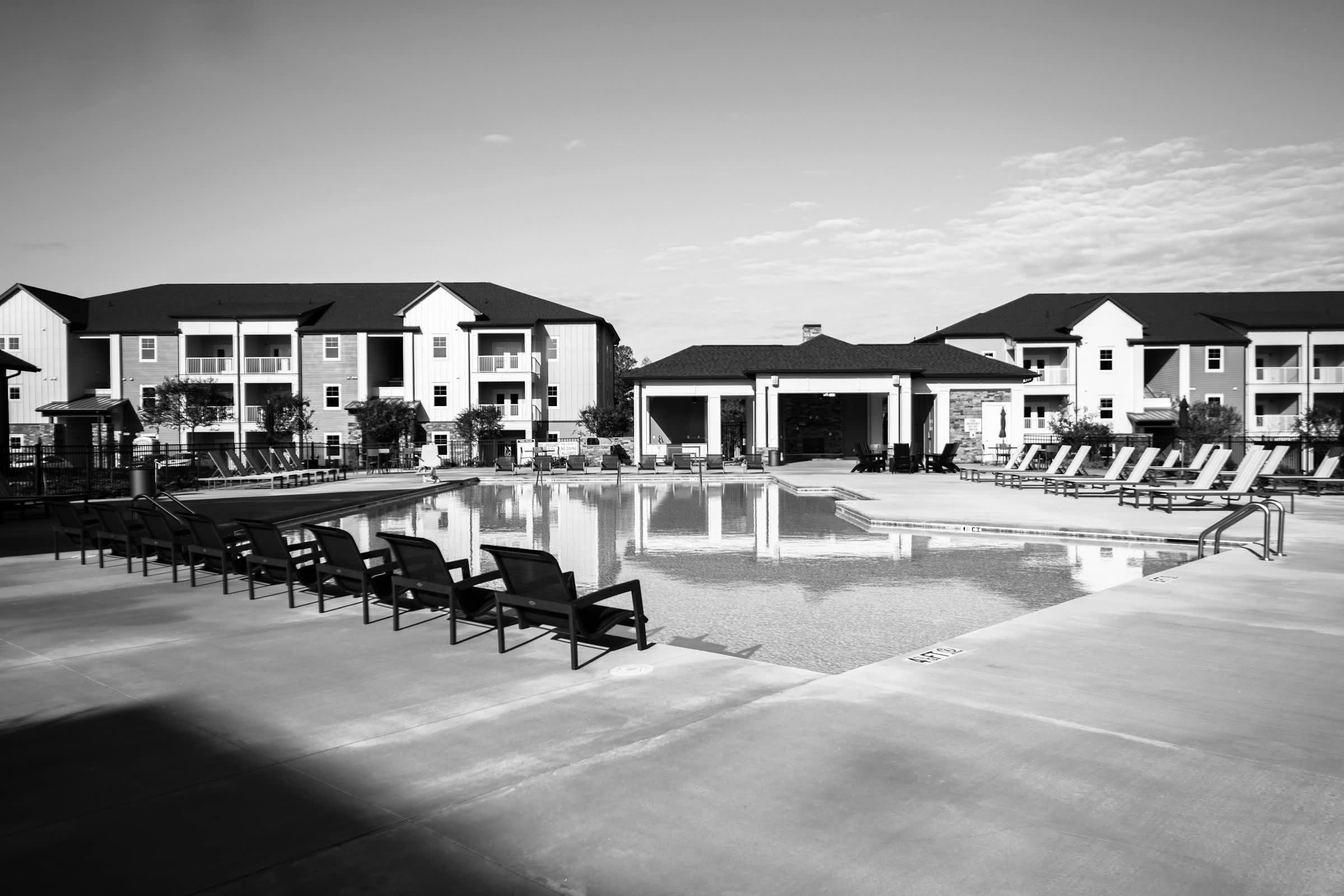Three-story apartment buildings and a clubhouse around a community pool