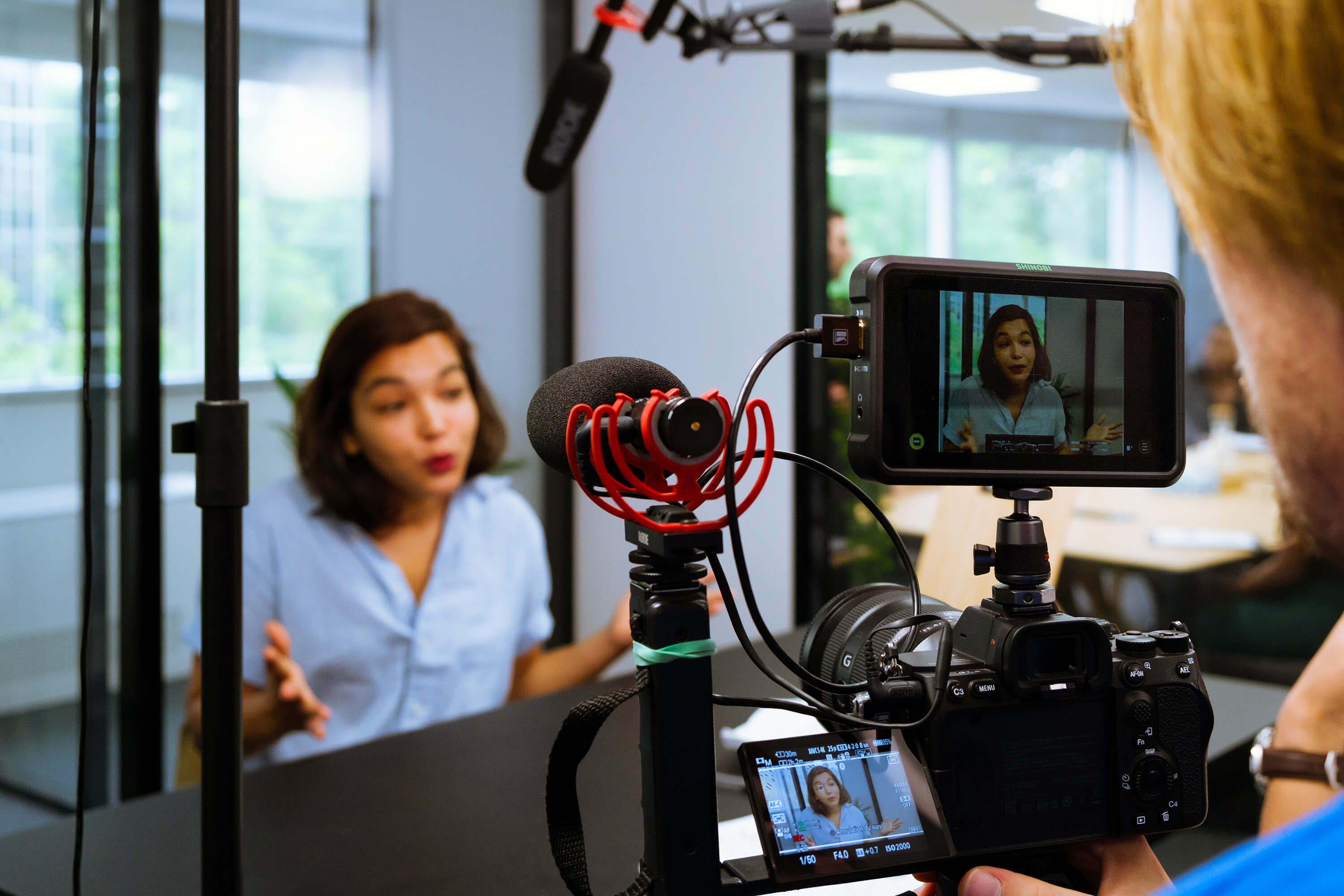 Tournage d'une interview en entreprise : opérateur au boîtier et micro-canon, intervenante face caméra