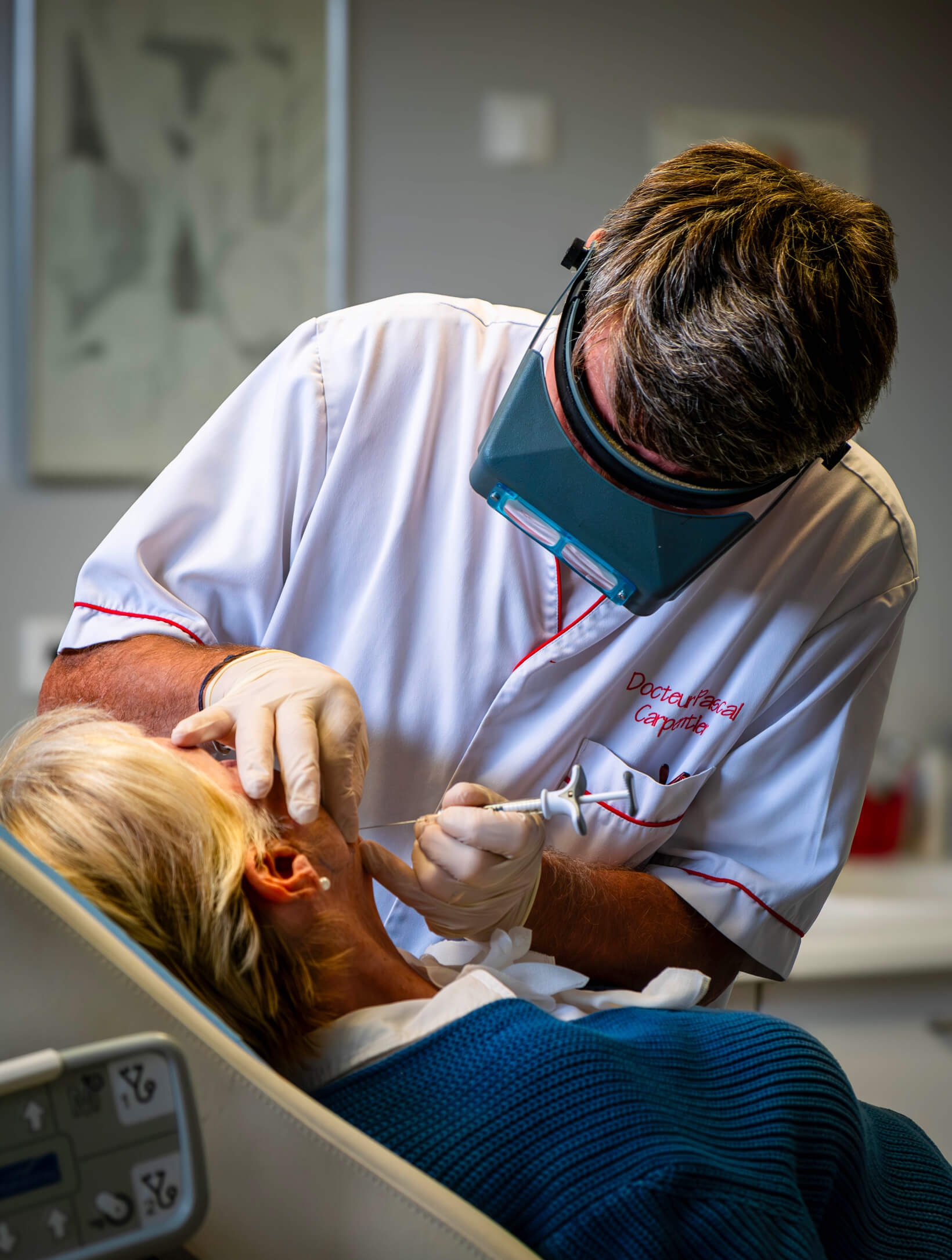 Chirurgien-dentiste en blouse blanche soignant une patiente au fauteuil