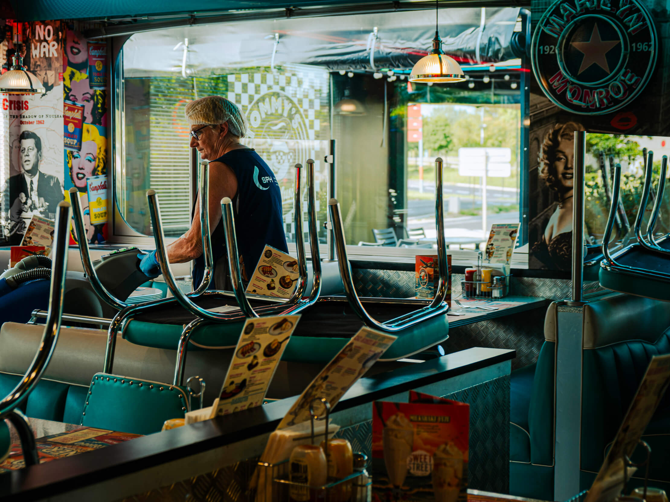 Salle d'un restaurant américain aux banquettes turquoise, serveuse derrière le comptoir