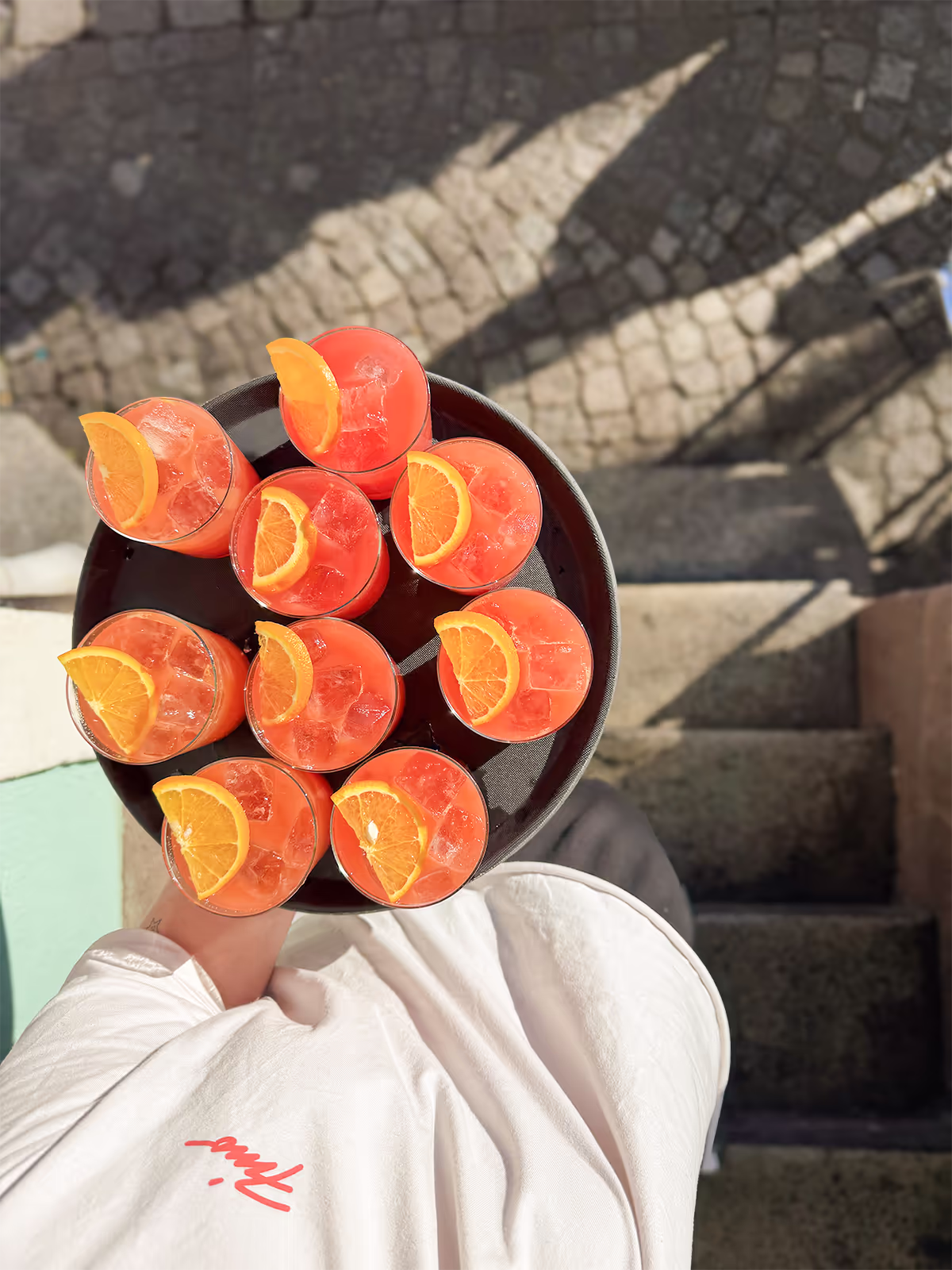 FINO Freiburg Catering: Servicekraft serviert Tablett mit Campari Orange und Orangenscheiben, von oben fotografiert