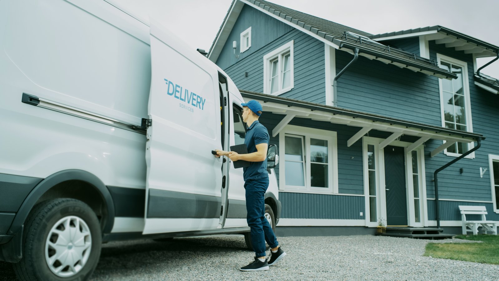 Courier opening the side door of a delivery van outside a house