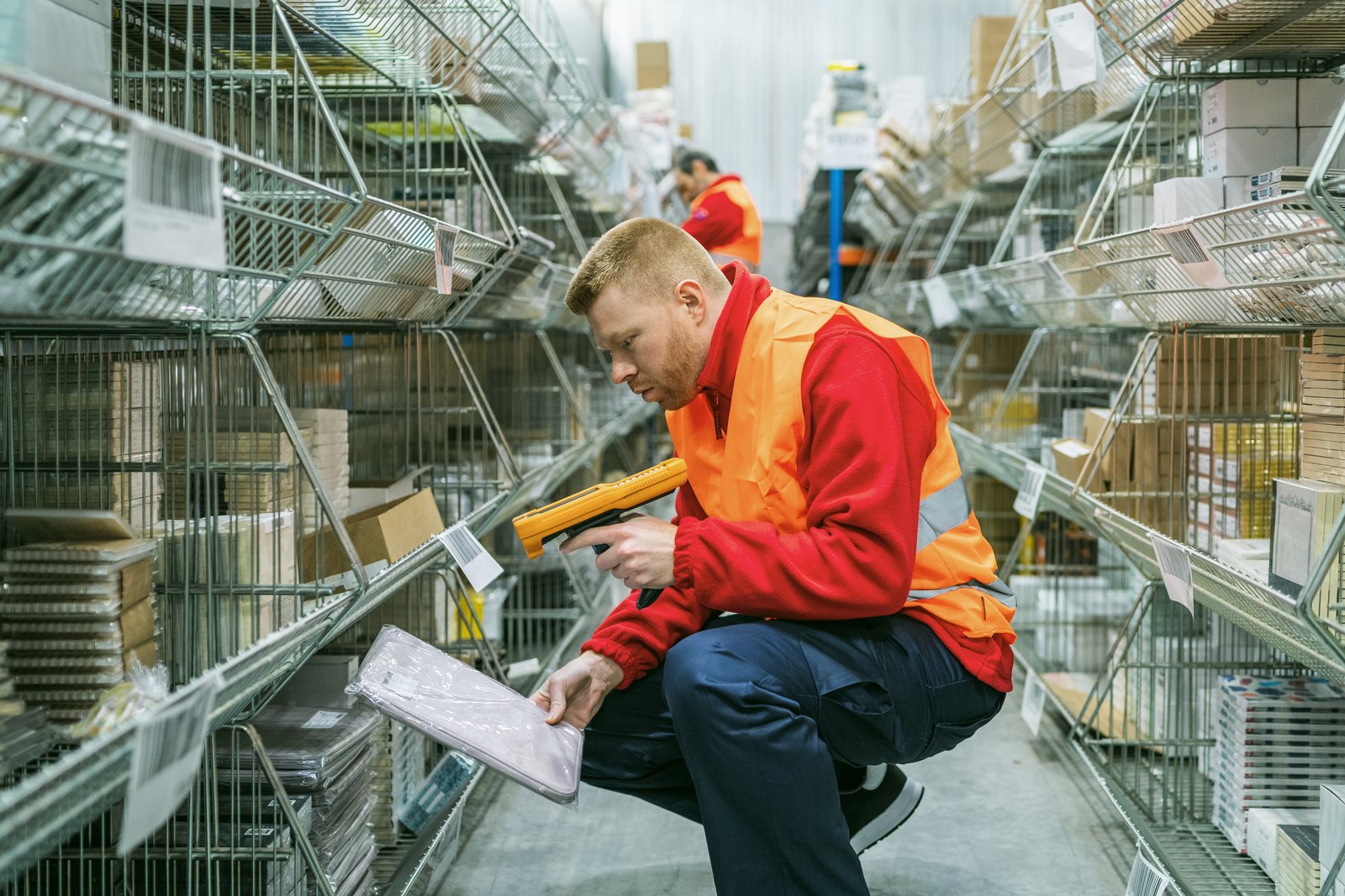 Warehouse operative checking stock against a handheld device in a racking aisle