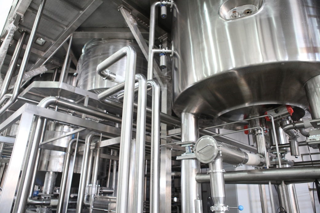 Interior view of a stainless steel industrial processing system with large tanks and interconnected pipes.