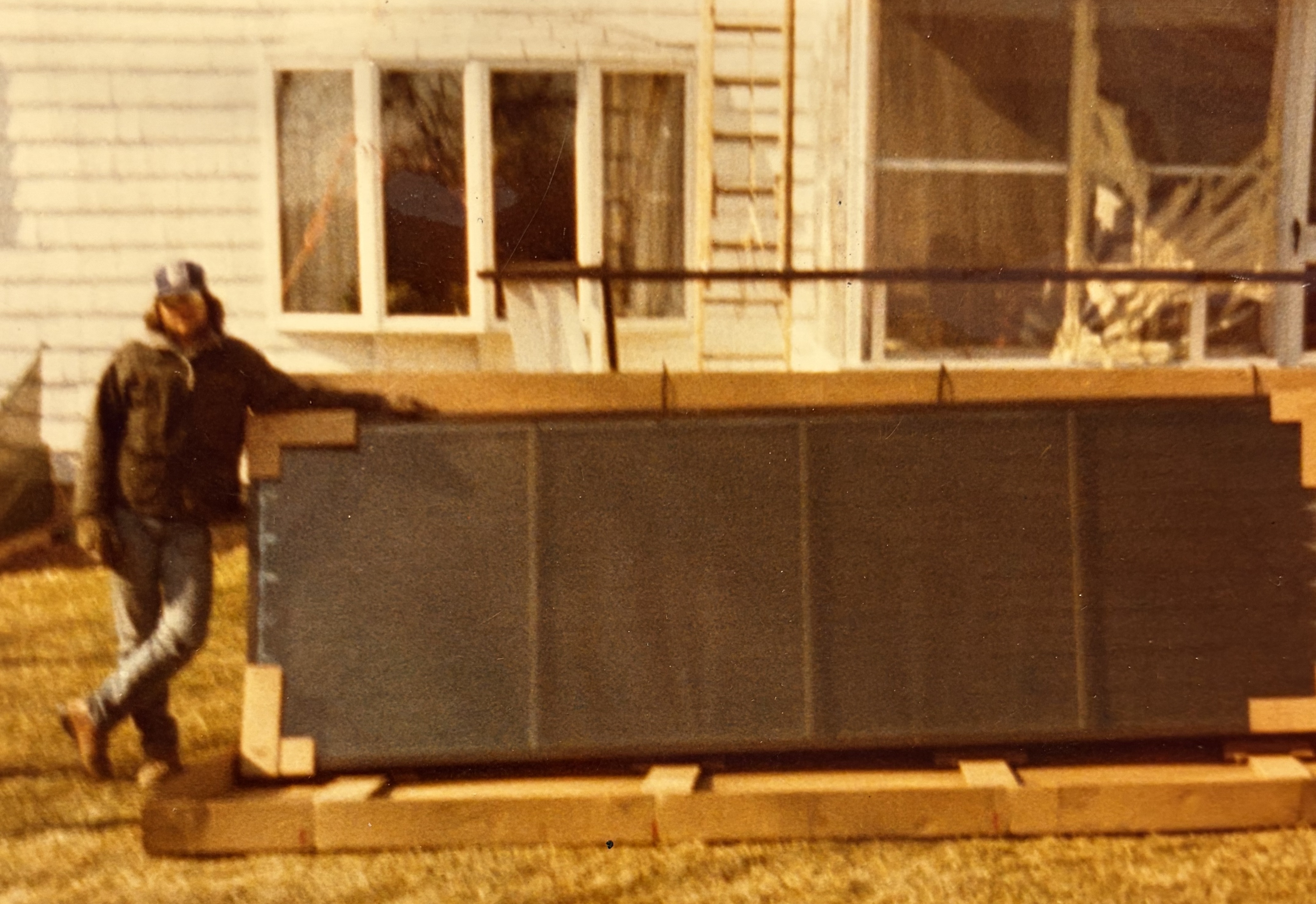 Bill Martin carrying a solar collector panel at a New England house in 1981