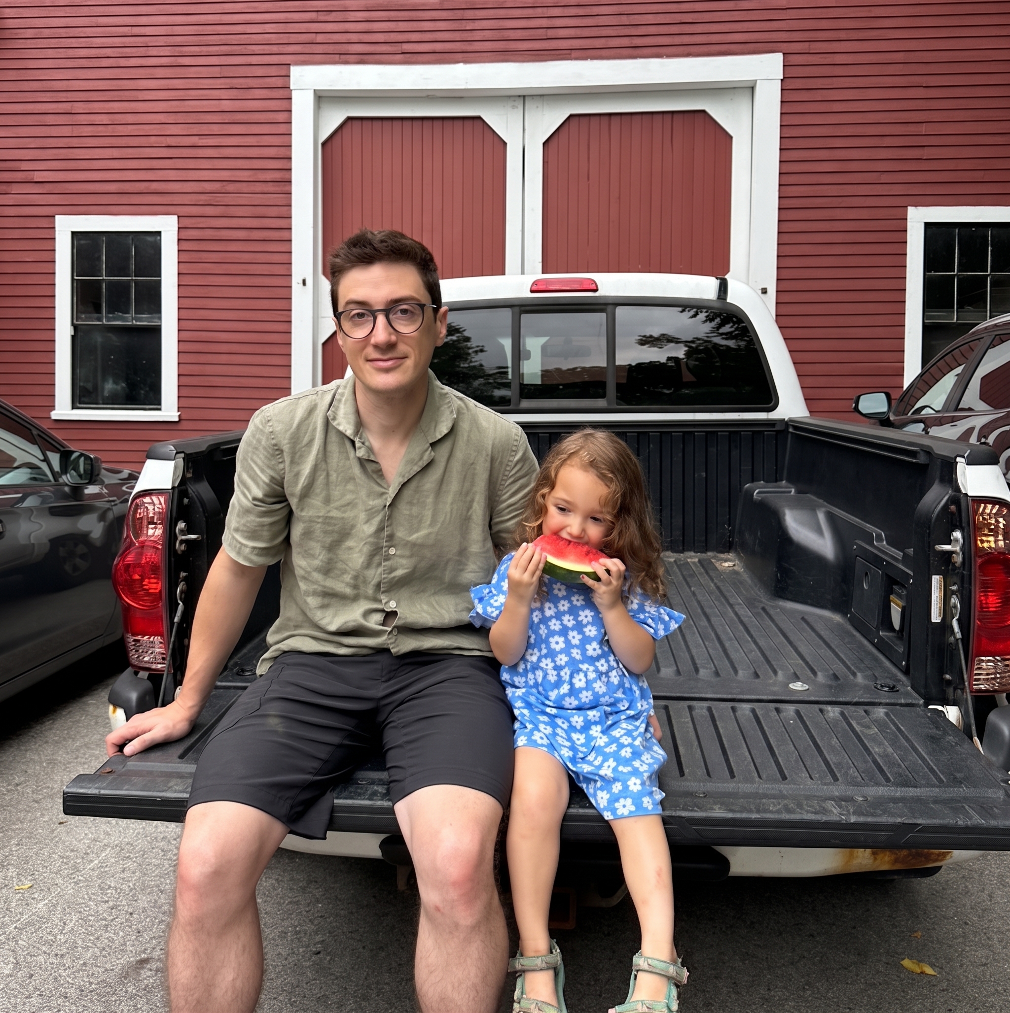 Sam Pierog, co-founder of WattsUp Renewable, sitting on a truck tailgate with his daughter