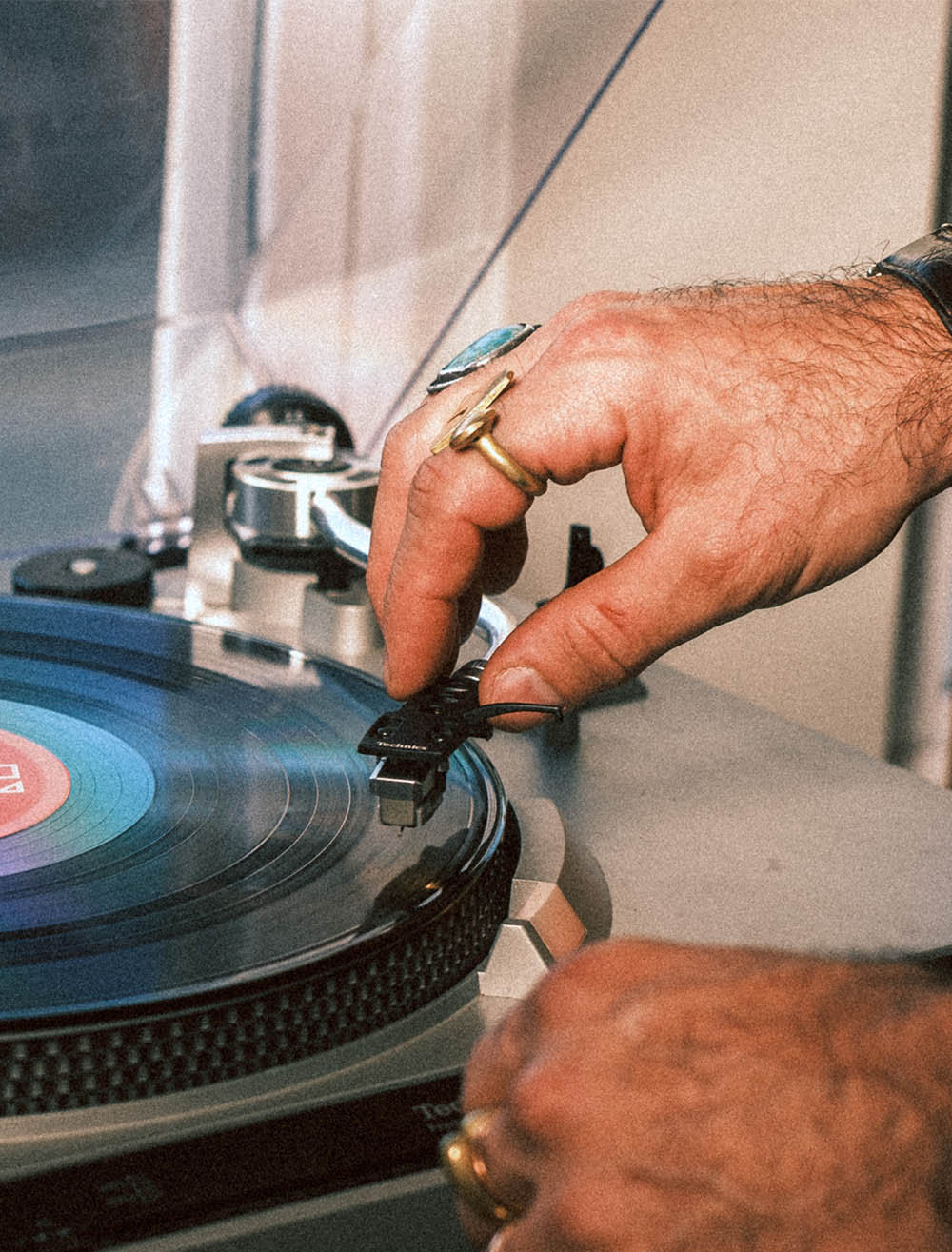 Close-up of a hand adjusting the needle on a turntable playing a vinyl record.
