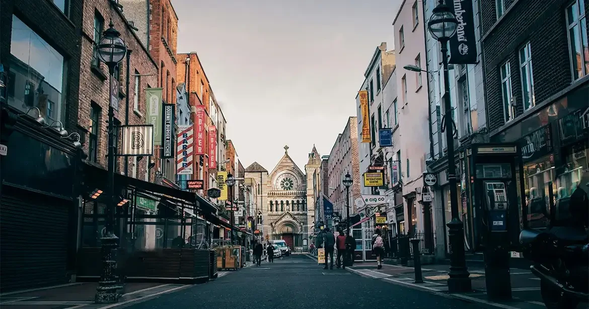 A street view in Dublin, Ireland, featuring a cobblestone road lined with shops and restaurants