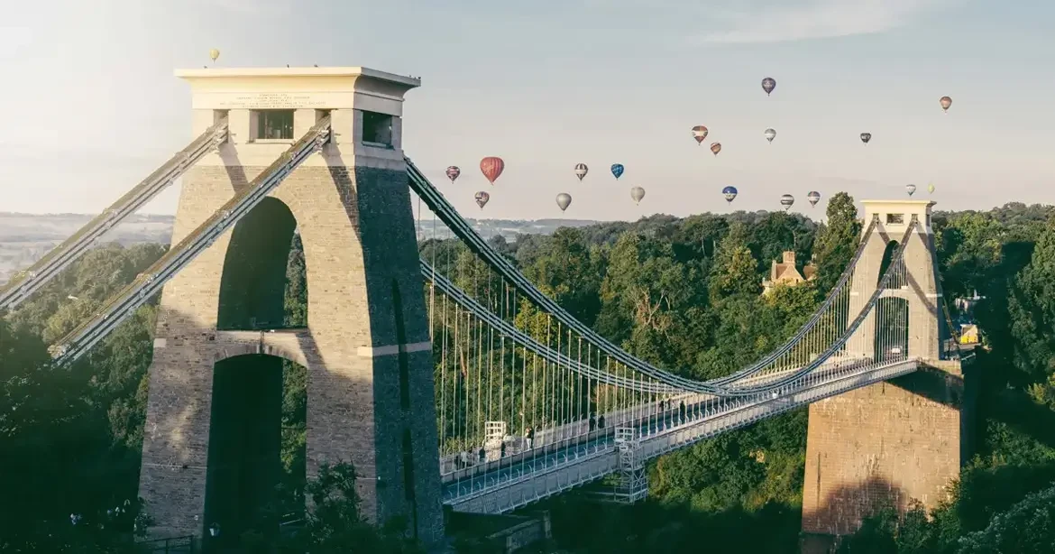 Clifton Suspension Bridge over the Avon Gorge in Bristol, with hot air balloons from the Bristol International Balloon Fiesta floating overhead
