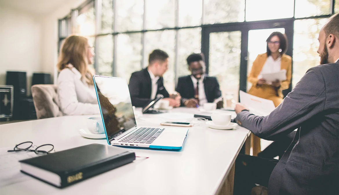 In-house legal professionals in a meeting around a conference table, reviewing documents and a laptop