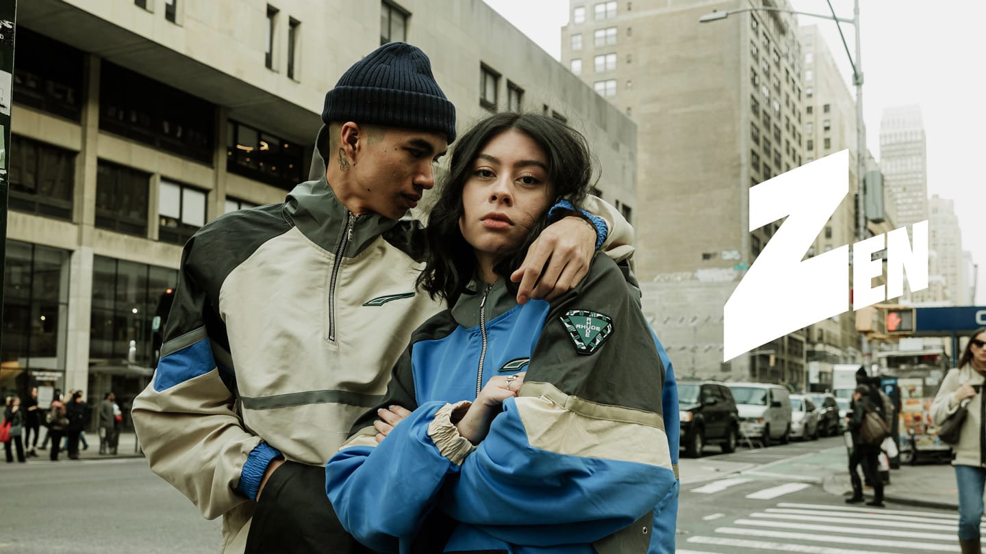 Man and woman embracing on a city street, wearing streetwear jackets, with a large "Zen" logo overlaid.