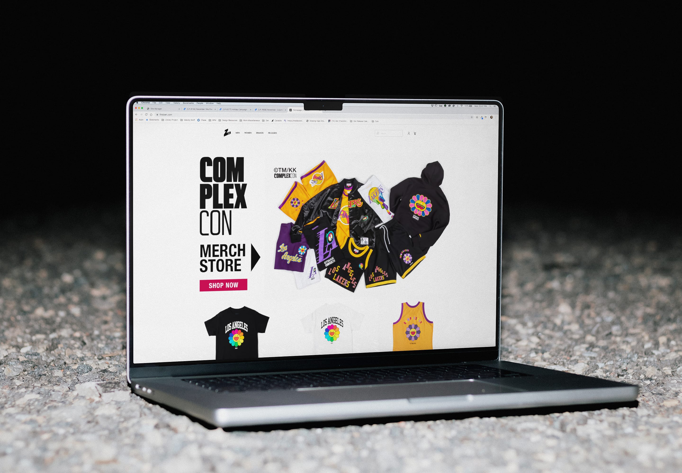 Laptop on gravel displaying Zen's ComplexCon merch store landing page with Lakers-themed streetwear.