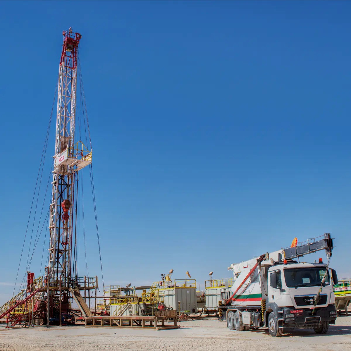 Workover rig alongside a mobile crane truck