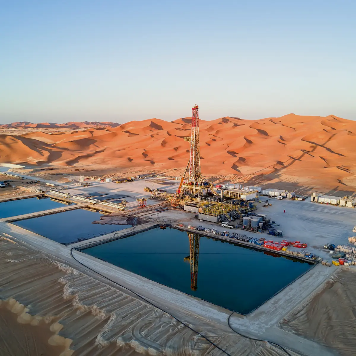 Aerial view of a desert drilling site with rig and reserve pits
