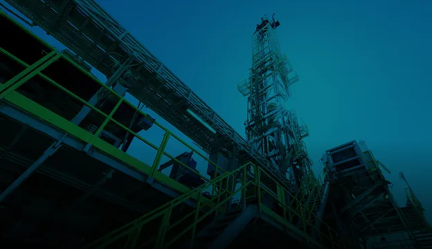 Low-angle view of a drilling rig illuminated at night