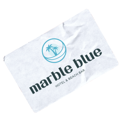 White card with a blue circular logo featuring two palm trees and waves above the text 'marble blue' and 'hotel & beach bar' in black font on a slightly crumpled surface.