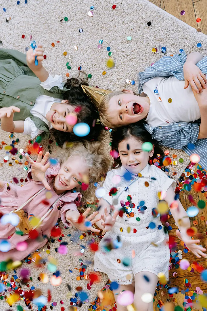 Young children laying on the floor laughing with excitement at a children's birthday party