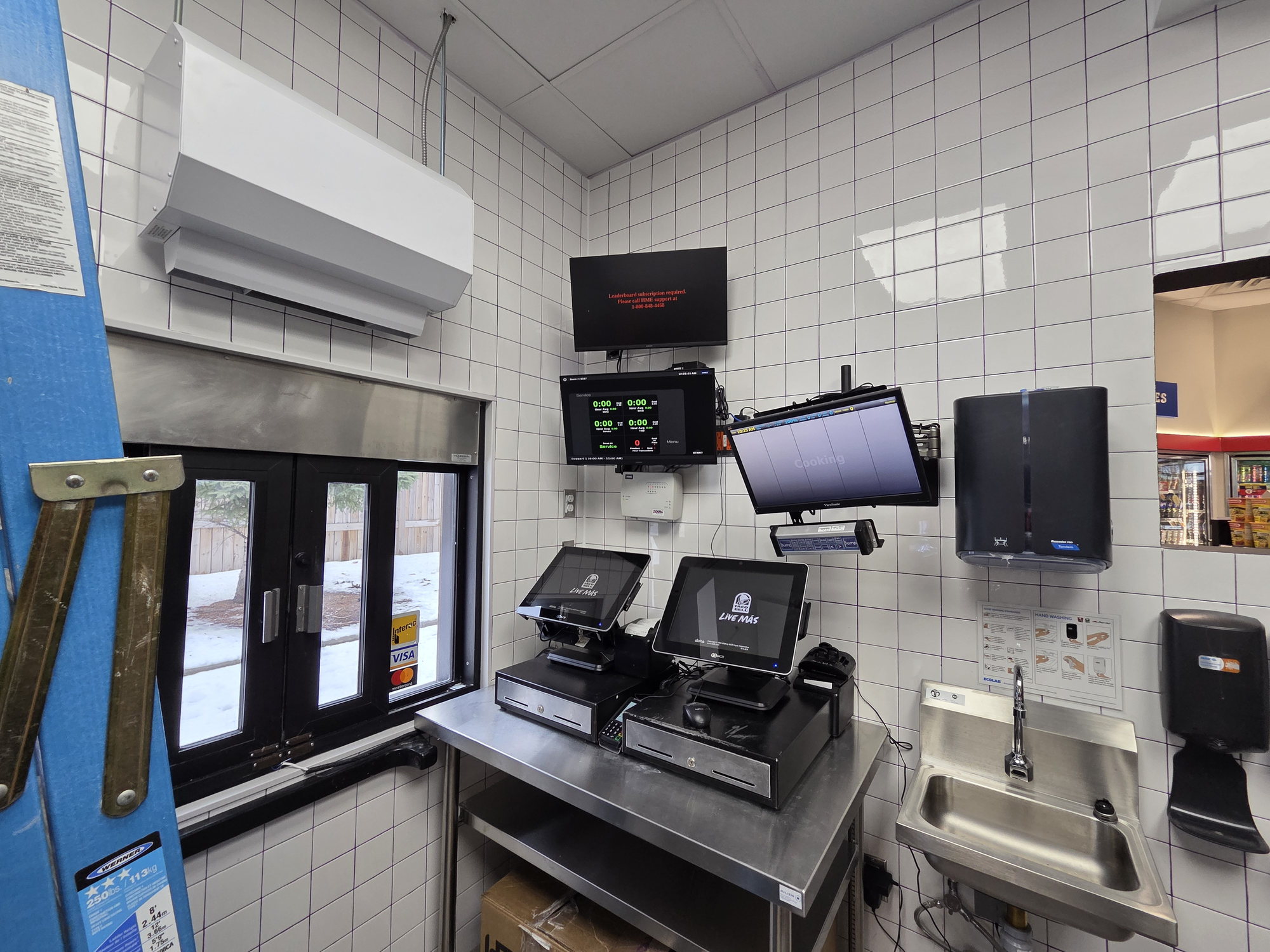 Finished order counter with POS terminals and kitchen display screens in a franchise quick-service build-out