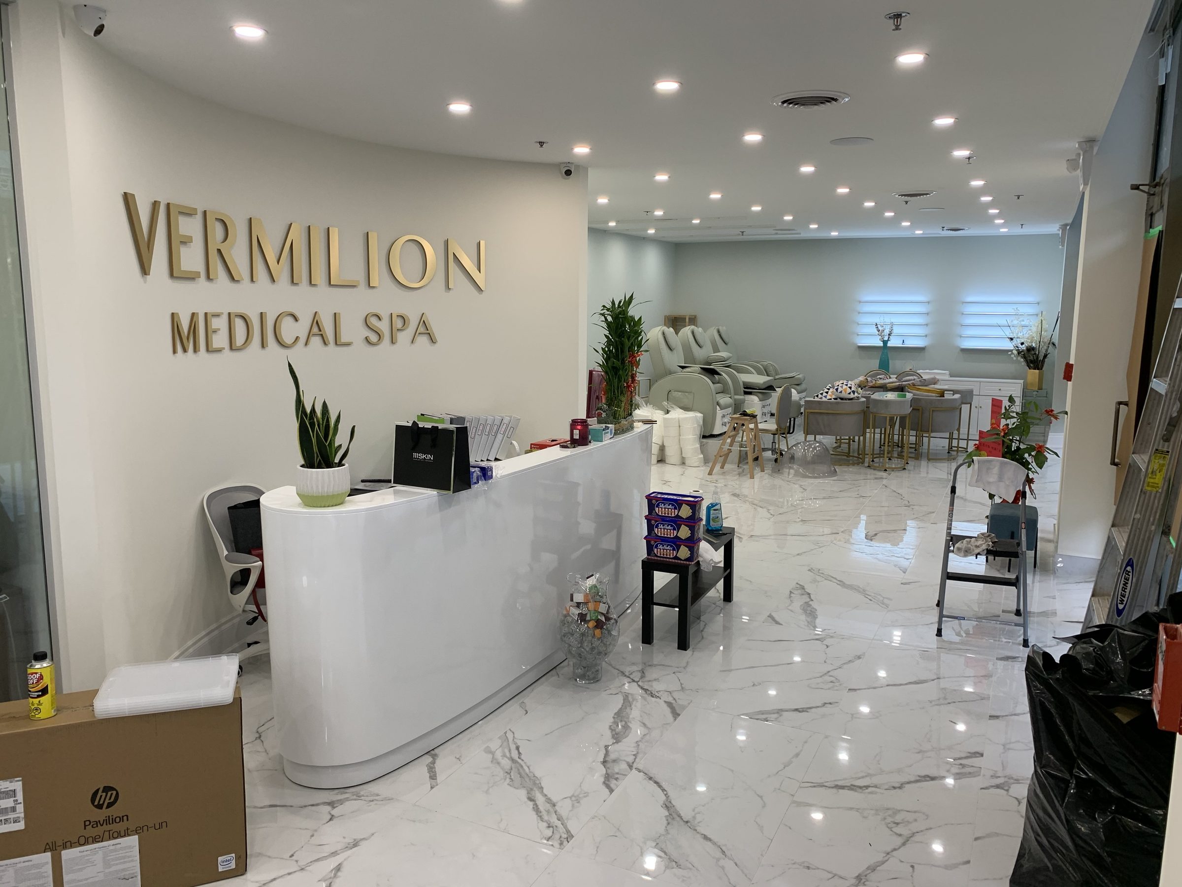 Finished clinic reception with custom curved desk, brand signage and marble flooring in a completed GTA commercial fit-out