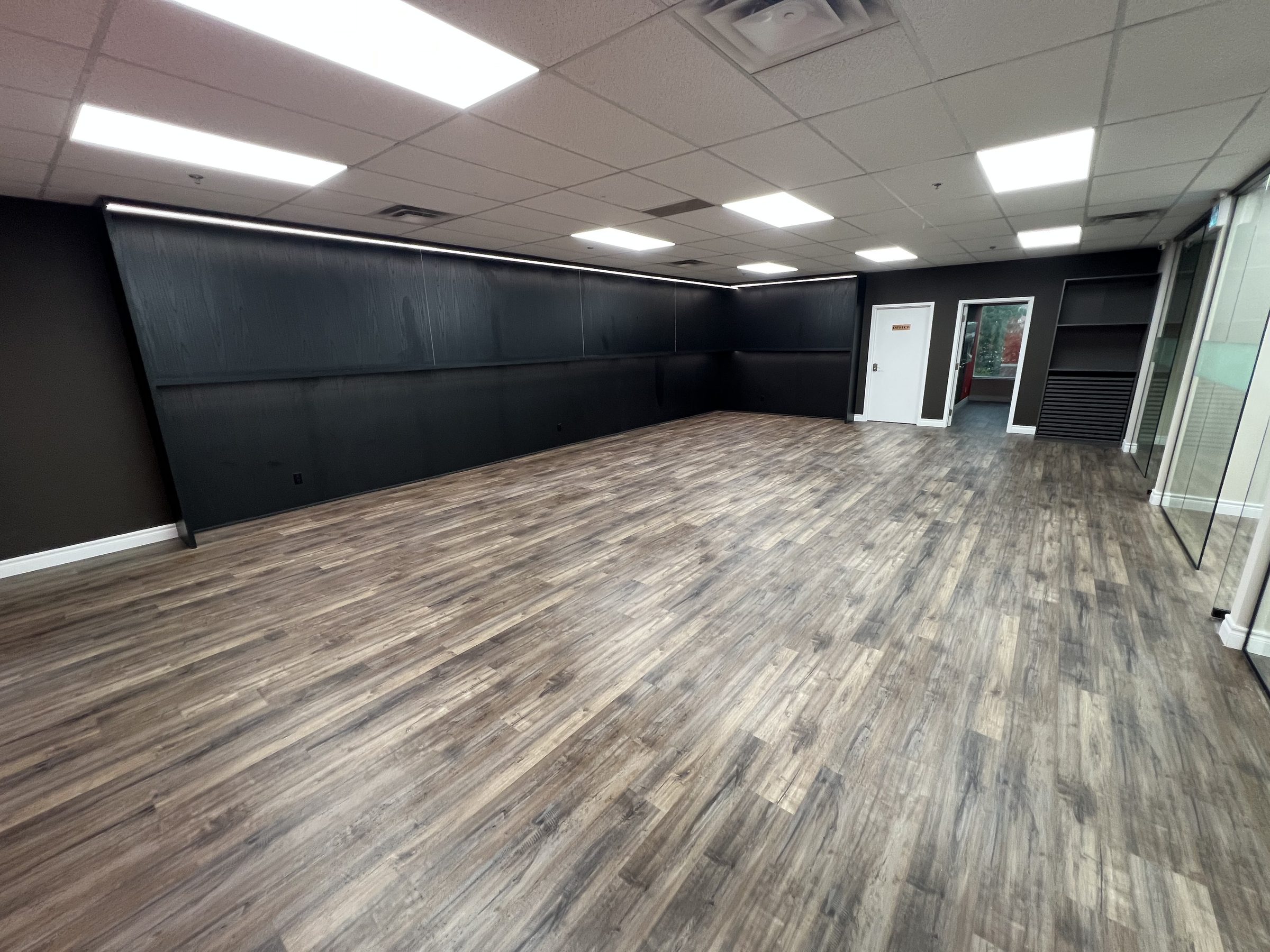 Finished commercial studio space with acoustic feature wall and vinyl plank flooring, completed by Buildup Contracting