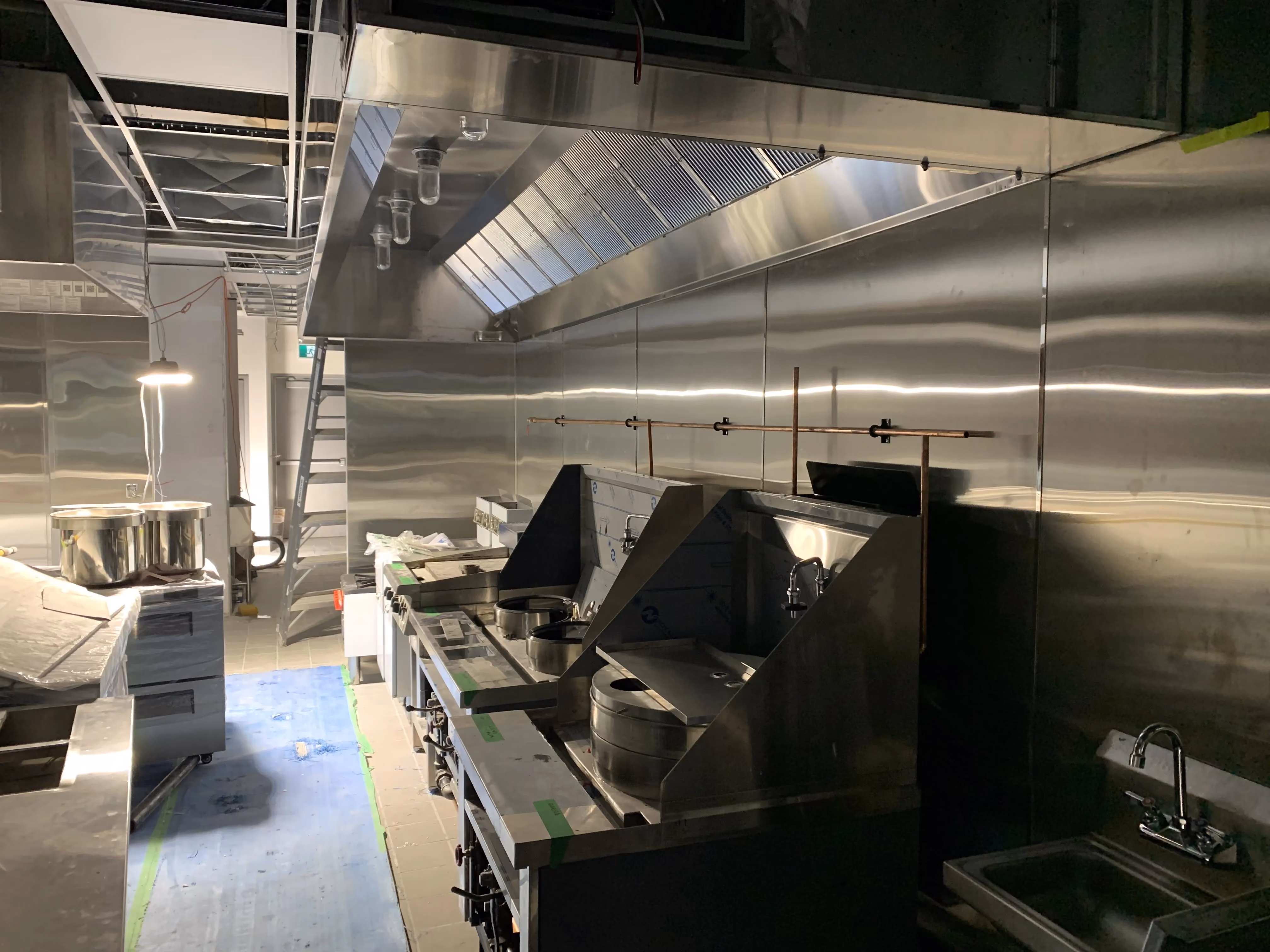 Commercial kitchen with stainless steel cook line and exhaust hood, restaurant build-out in the GTA