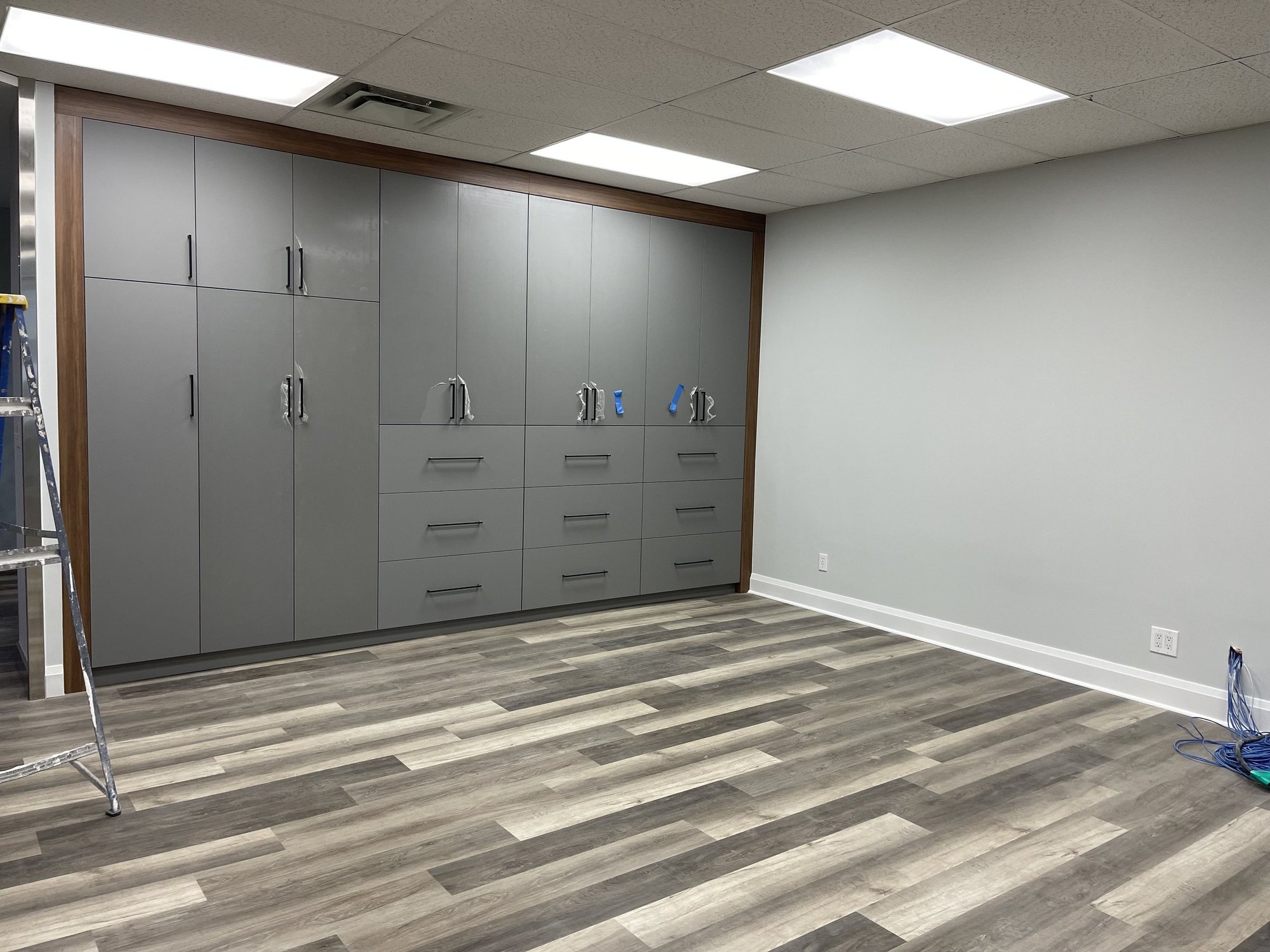 Custom full-height storage wall with walnut trim in a completed 2,000 sf Richmond Hill office fit-out