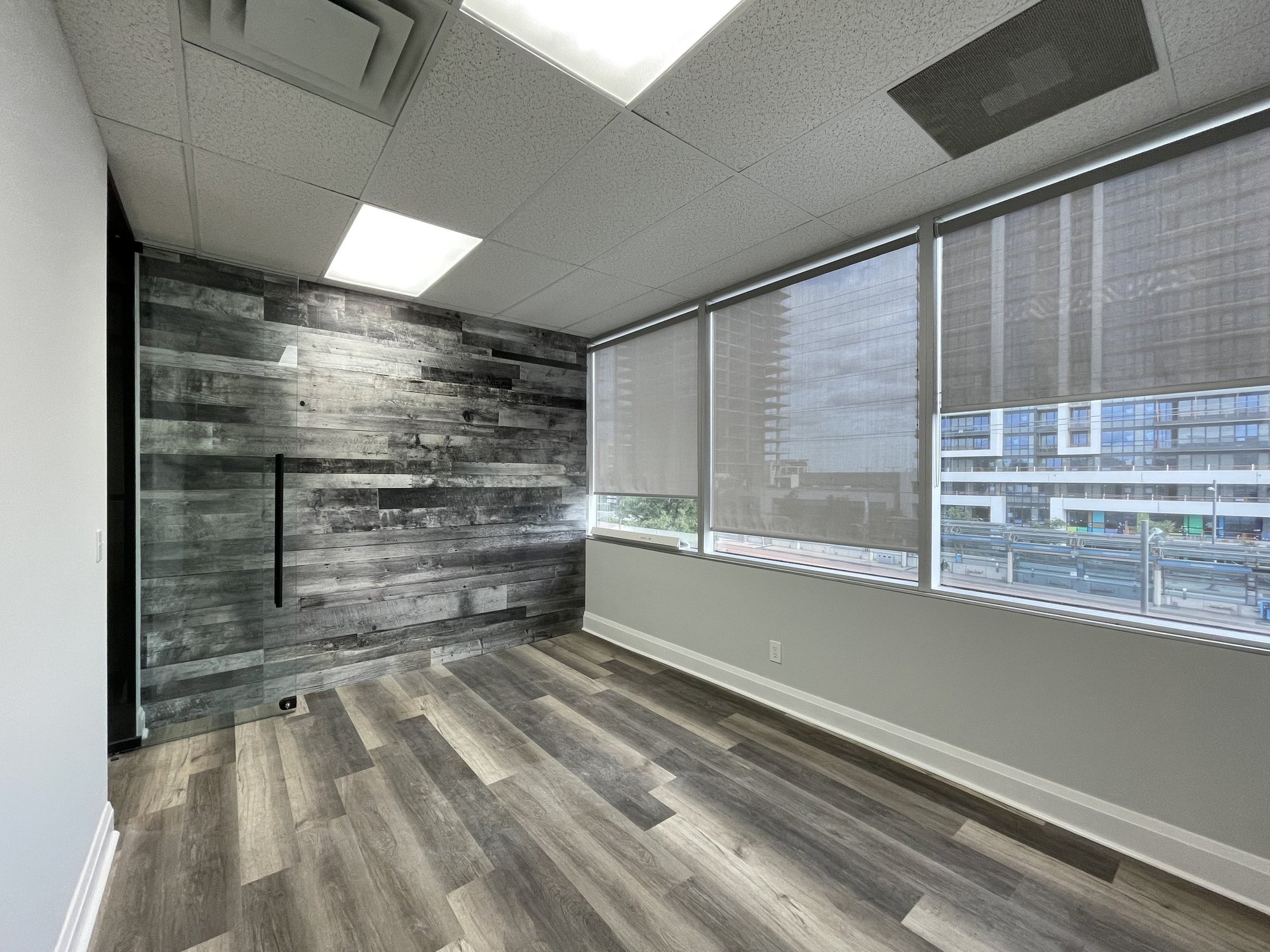 Private office with timber-plank feature wall and frameless glass sliding door in a Richmond Hill office fit-out