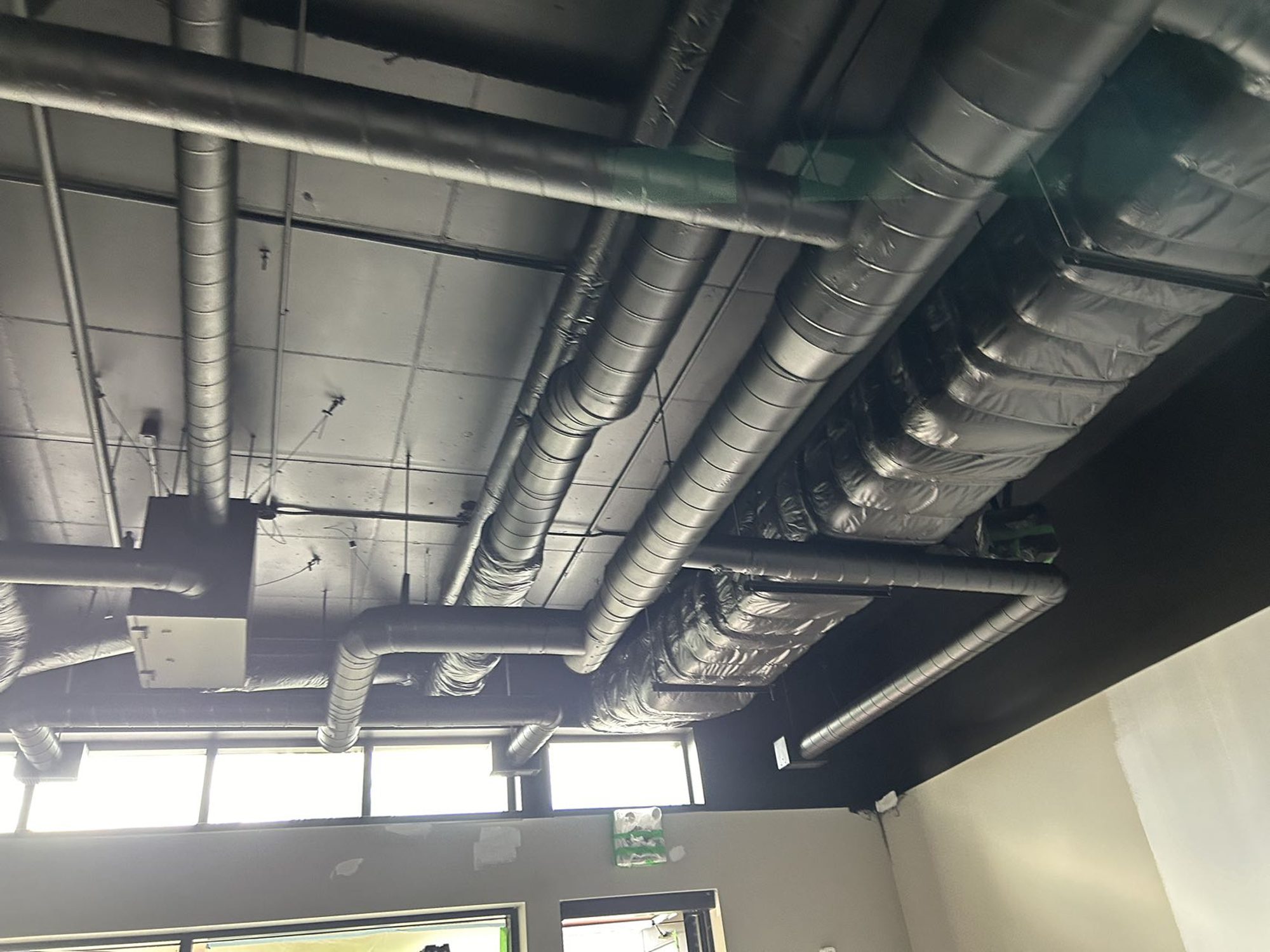 HVAC ductwork and electrical conduit rough-in above the open ceiling of a Mississauga bubble tea shop