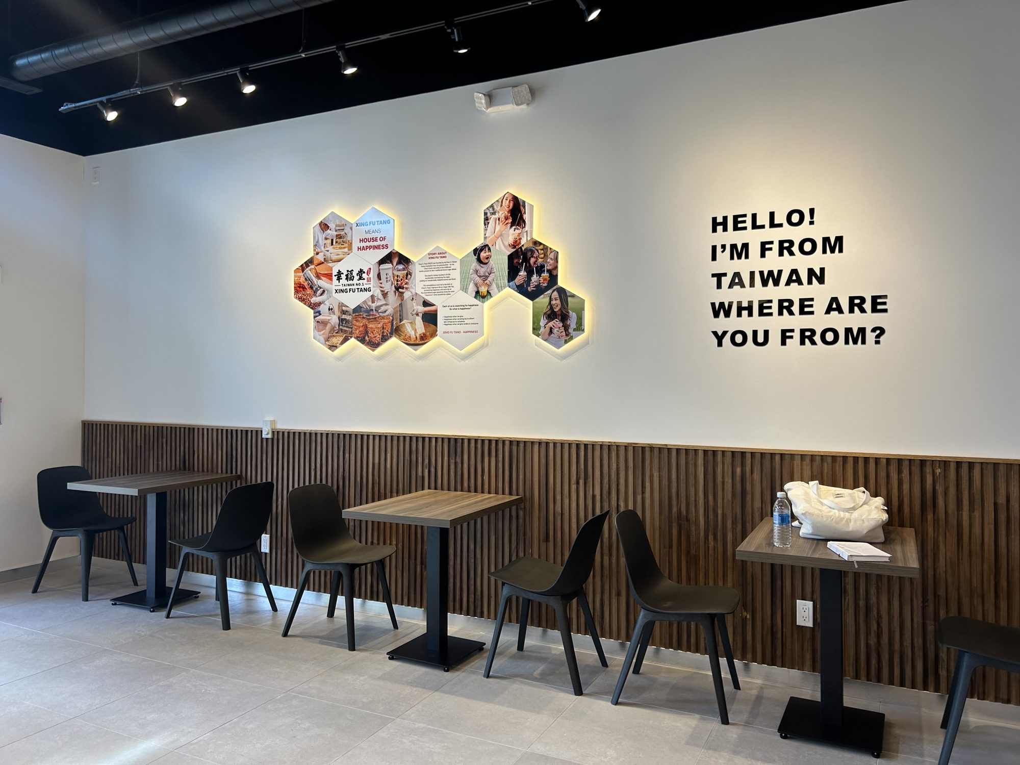 Finished dining area with wood-slat wainscot and backlit feature wall in a Mississauga bubble tea shop