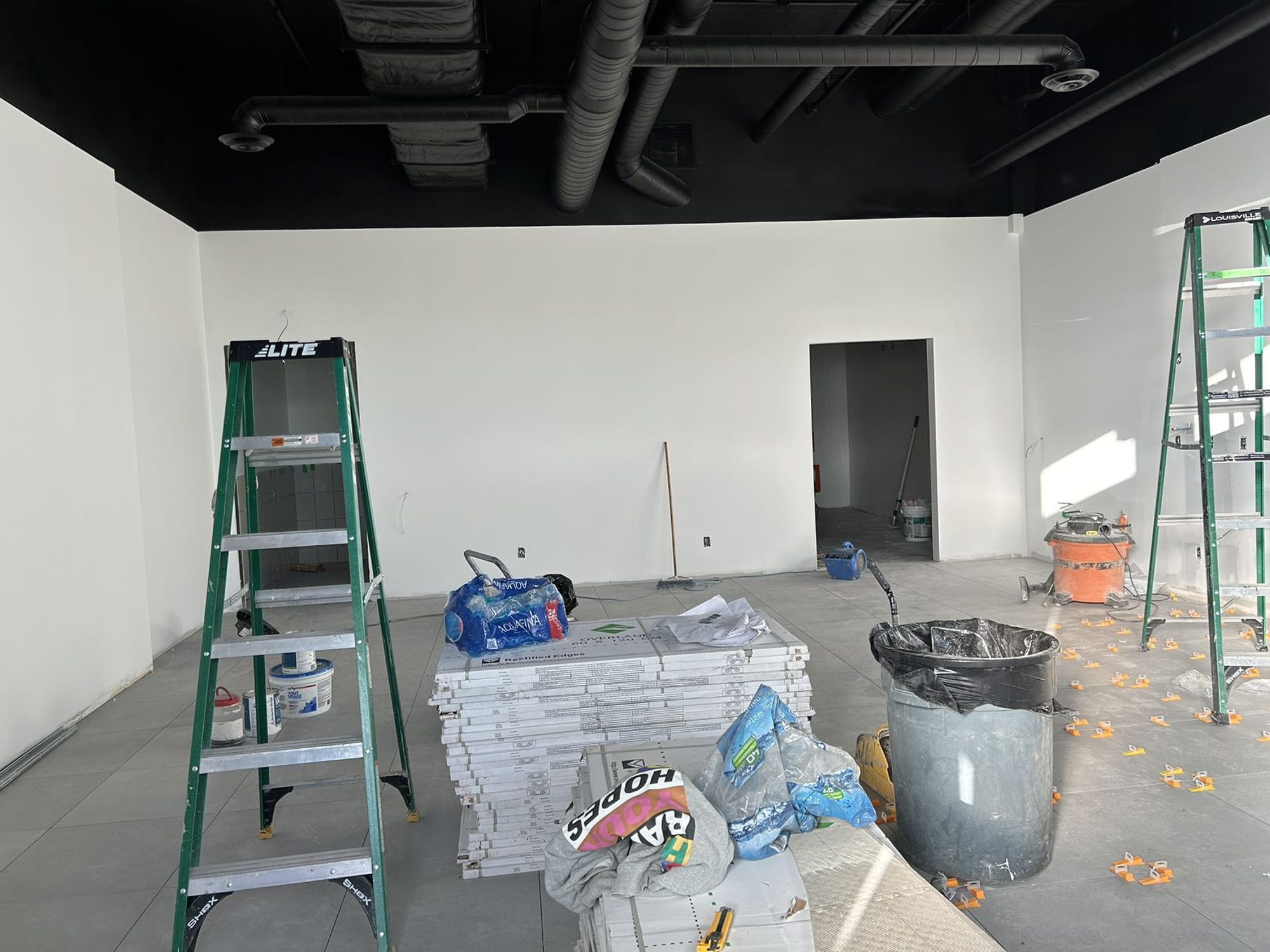 Exposed structure and ductwork painted black over primed walls in a Mississauga bubble tea shop