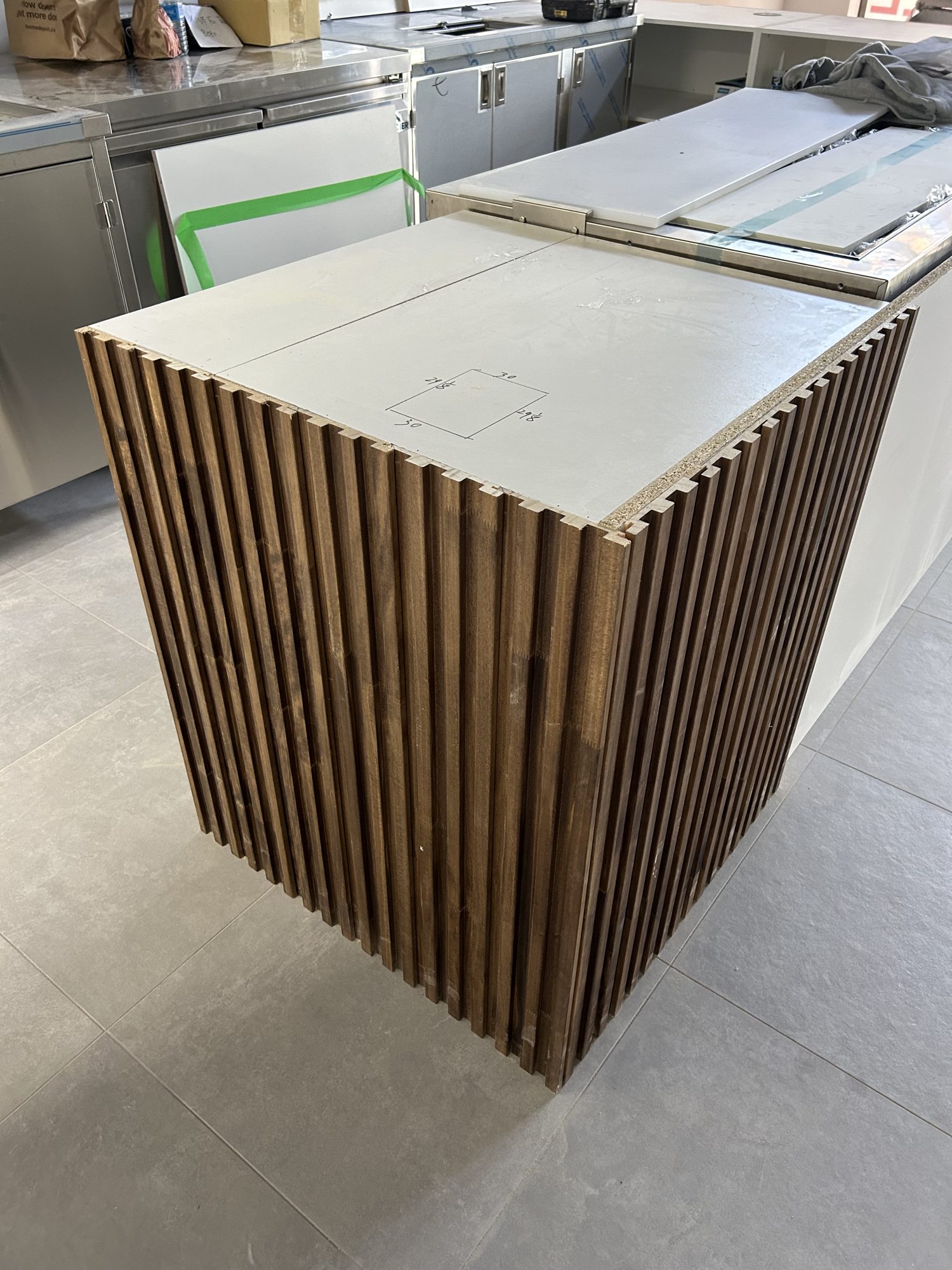 Wood-slat service bar millwork under fabrication during a bubble tea shop build-out