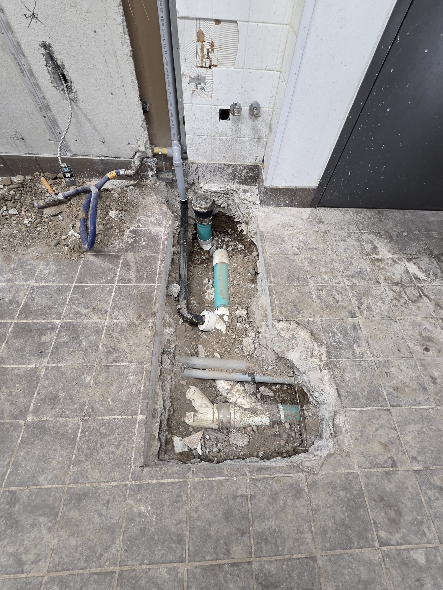 Saw-cut trench and new drain lines roughed in below the slab of an operating gas station store