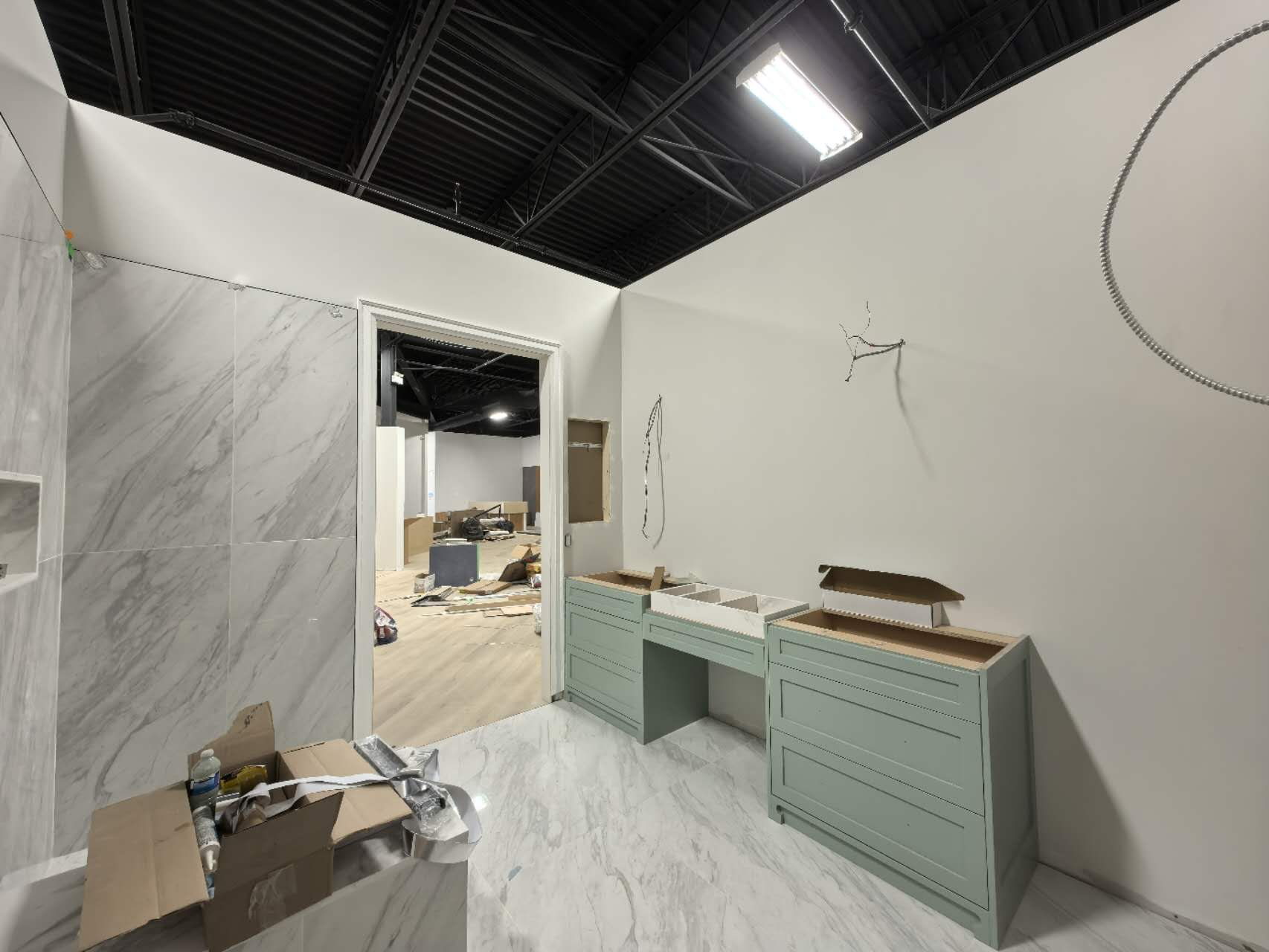 Marble-clad bathroom vignette with sage green vanity in a Toronto design showroom fit-out