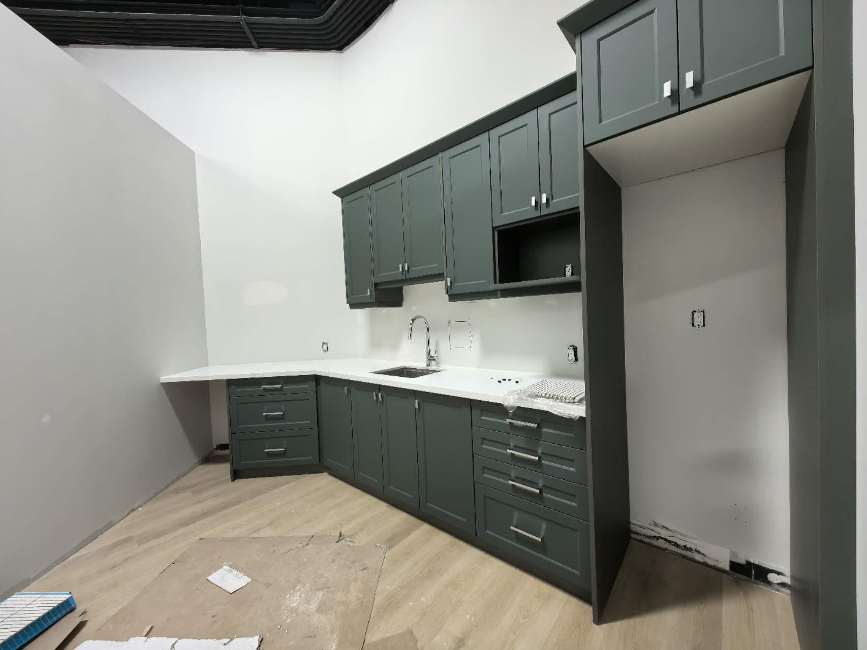 Dark green shaker kitchen display with white quartz counter in an Etobicoke design showroom
