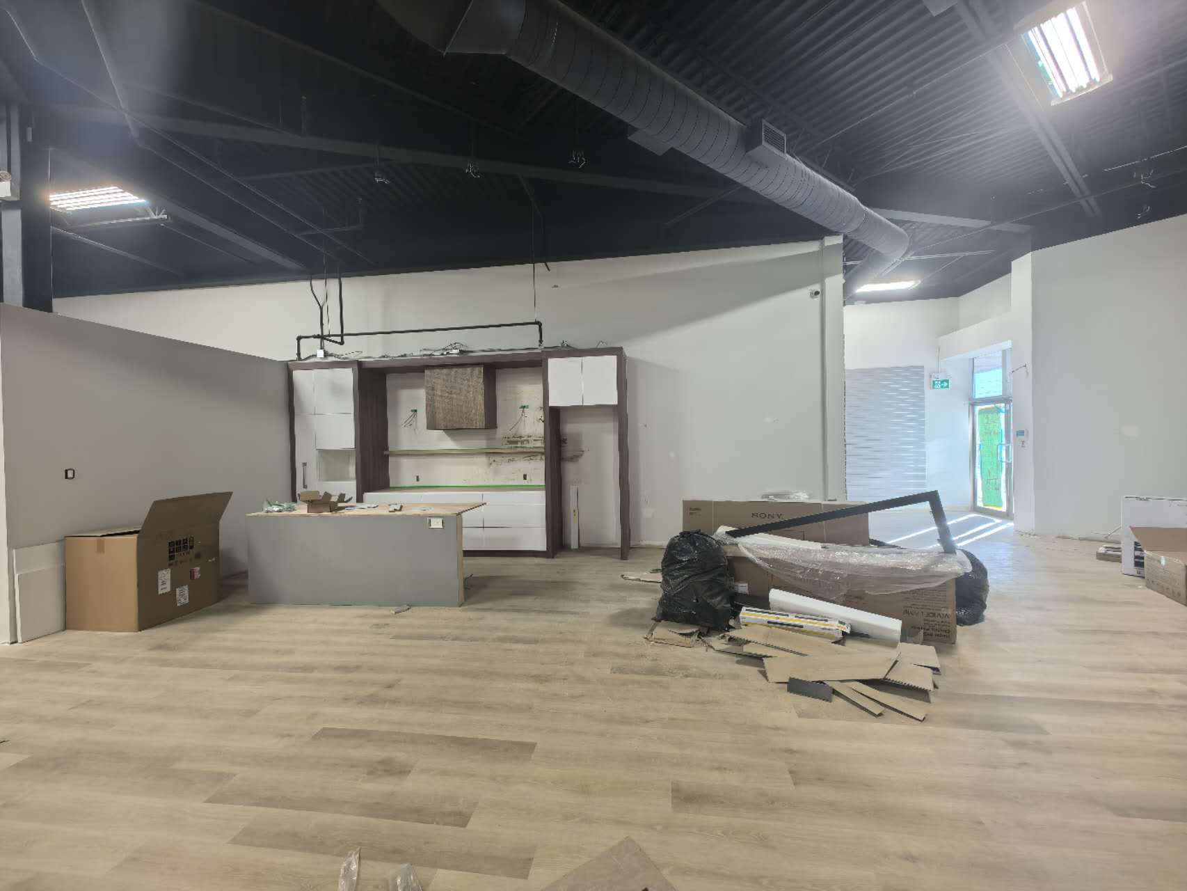 Showroom display island and kitchen vignettes under a blacked-out open ceiling