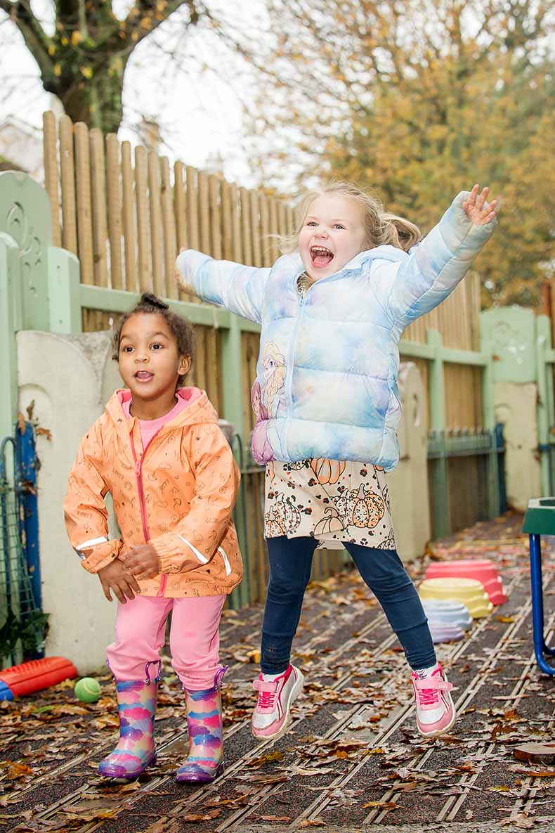 Two smiling children jumping for joy outside