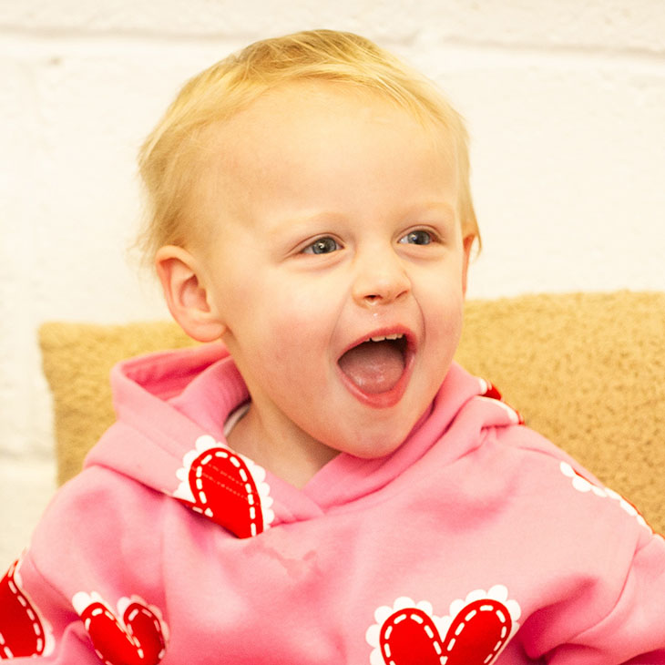 Toddler  in pink top with wide smile